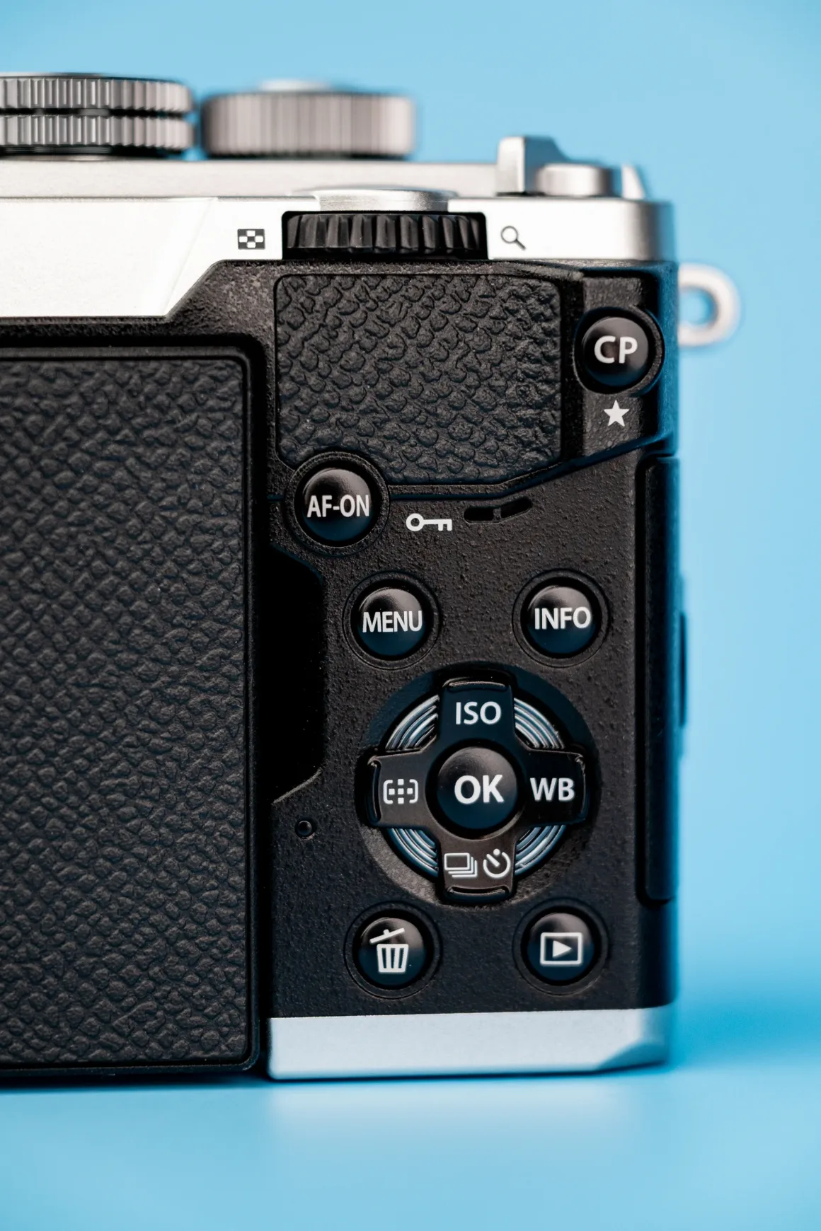OM System PEN İncelemesi: Tanıdık Ama Son Derece Şık 27 A close-up view of the back of a digital camera, showing buttons labeled AF-ON, MENU, INFO, OK, ISO, WB, a trash icon, and a playback icon against a blue background.