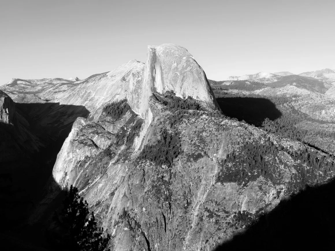 Apple, iPhone 18 Pro’daki Değişken Diyaframı Anlatıyor 24 Half Dome’un sarp granit yüzeyinin ormanlık dağ sırtı üzerinde yükseldiği siyah-beyaz manzara.