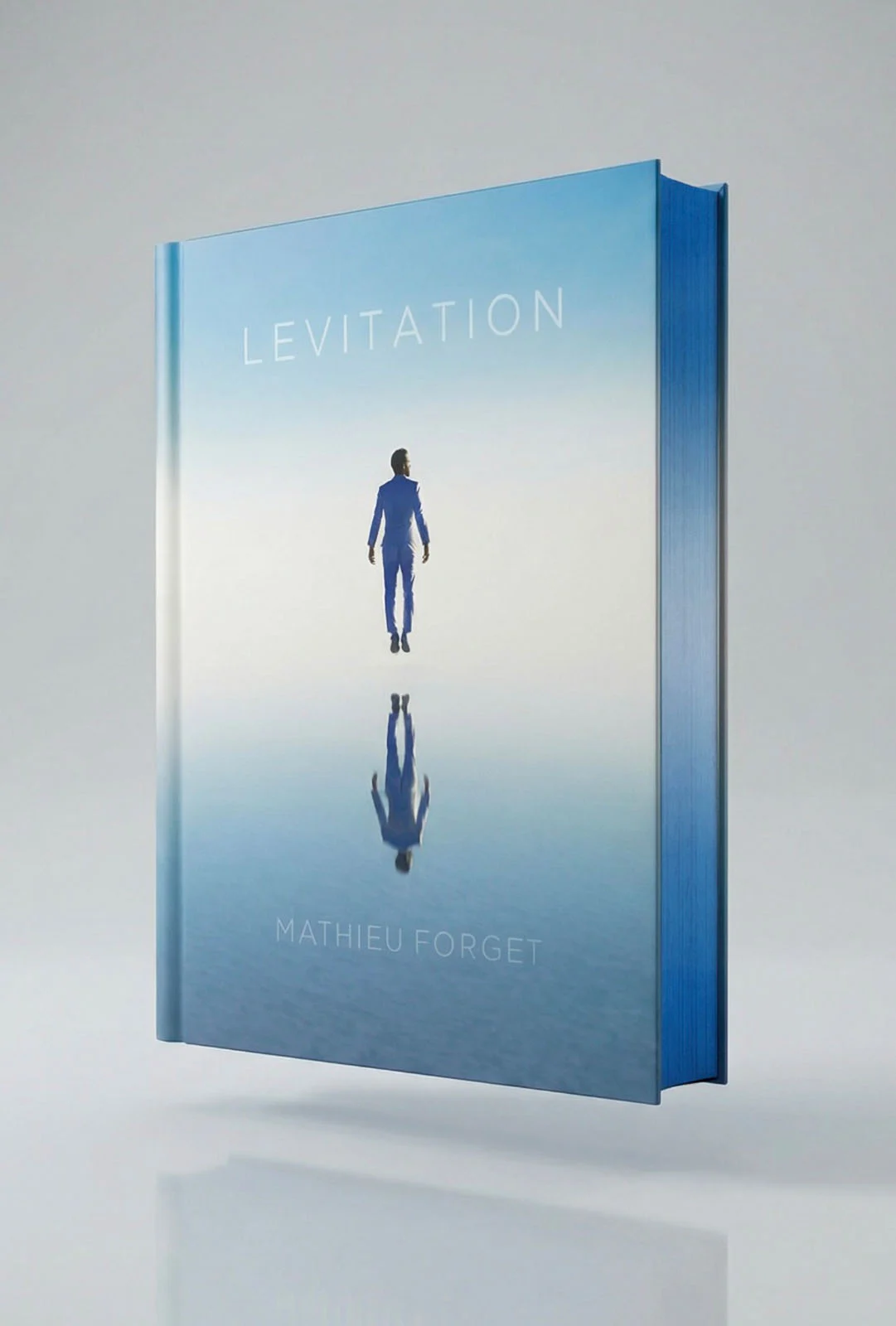 Mathieu Forget’nin “Levitation” adlı kitabı dik biçimde duruyor; kapağında açık mavi gökyüzüne karşı yansıtıcı bir yüzeyin üzerinde havada süzülen mavi takım elbiseli bir adam görülüyor.