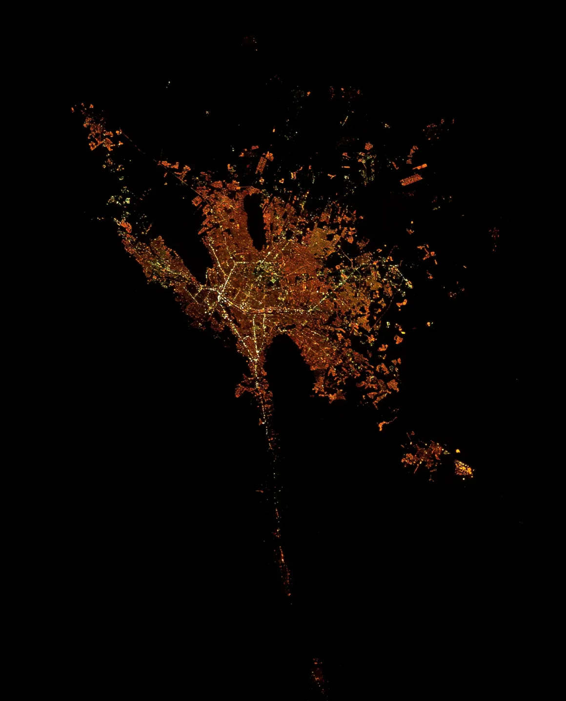 Astronotun Önce-Sonra Fotoğrafları Kentlerin Turuncudan Beyaz Işığa Geçişini Gösteriyor 29 A satellite view of a city at night, showing a dense cluster of golden and white lights against a black background.