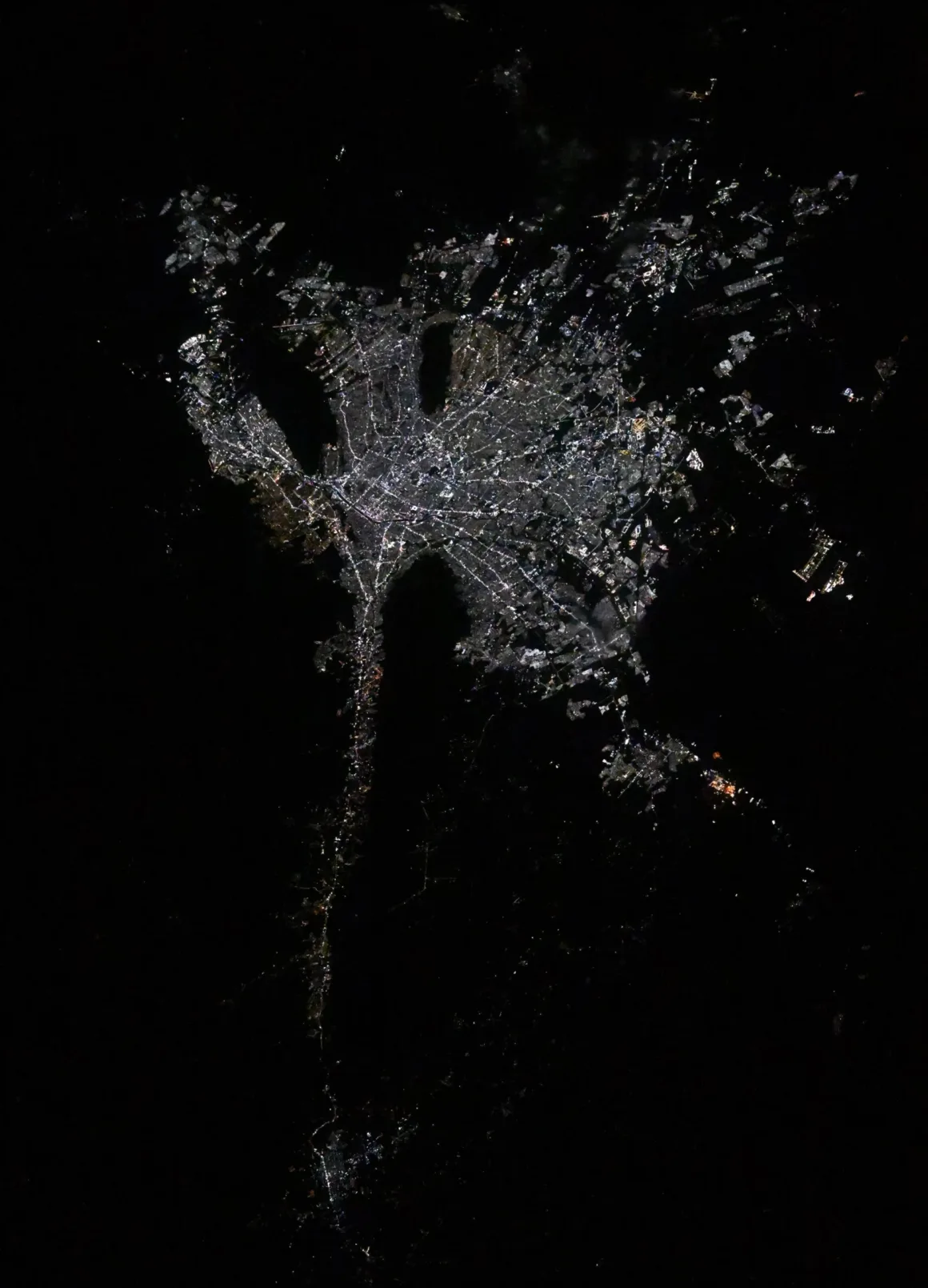 Astronotun Önce-Sonra Fotoğrafları Kentlerin Turuncudan Beyaz Işığa Geçişini Gösteriyor 30 A nighttime satellite view of a city’s glowing street grid, featuring a distinct, elongated urban sprawl extending southward.