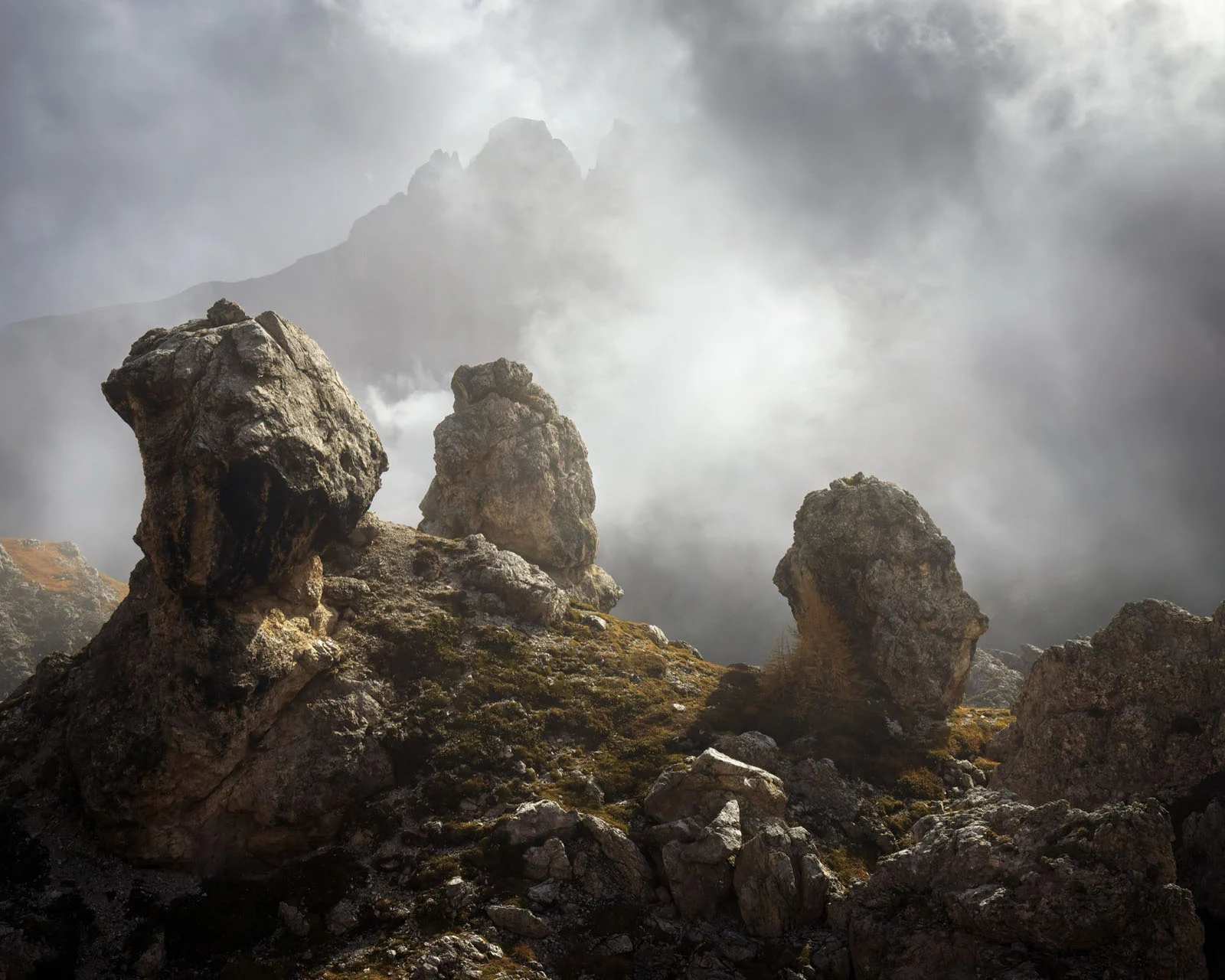 Natural Landscape Photography Awards 2026’nın Kazananları Açıklandı 19 Three large, jagged rock formations stand on a grassy, rocky slope beneath a cloudy, mist-filled mountain sky.