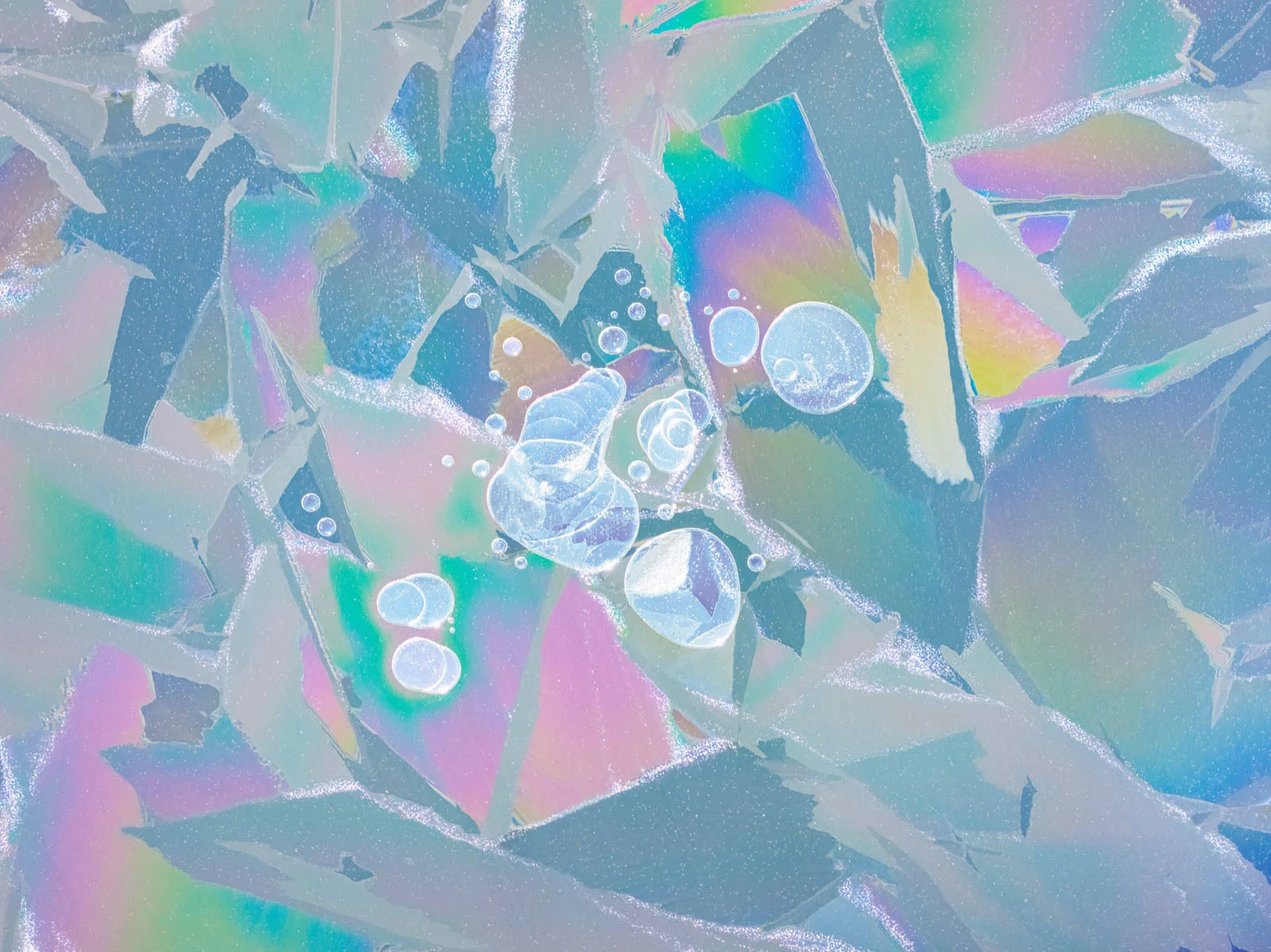 Natural Landscape Photography Awards 2026’nın Kazananları Açıklandı 37 Iridescent, angular shards of ice are scattered across a surface, with several clear, spherical air bubbles trapped within the center.