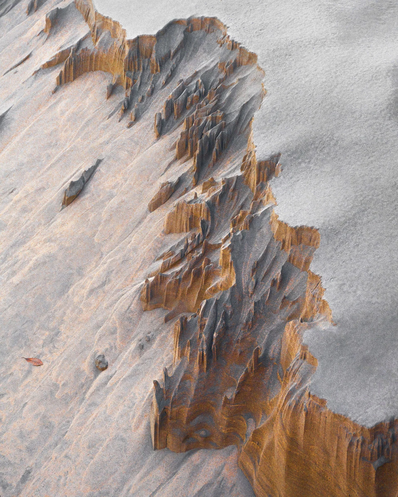 Natural Landscape Photography Awards 2026’nın Kazananları Açıklandı 38 A high-angle view of a sand dune featuring a sharp, eroded ridge with exposed layers of orange and grey sand.