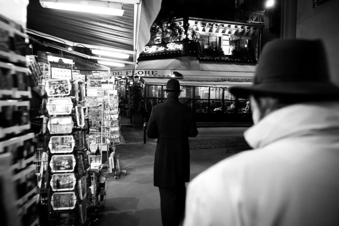Nicolas Rachline’ın Tekinsiz Fotoğraflarında Modern Yaşamın Yalnızlığı ve Güzelliği 22 Şapkalı ve paltolu bir kişi geceleri Café de Flore’a doğru yürürken görülüyor.