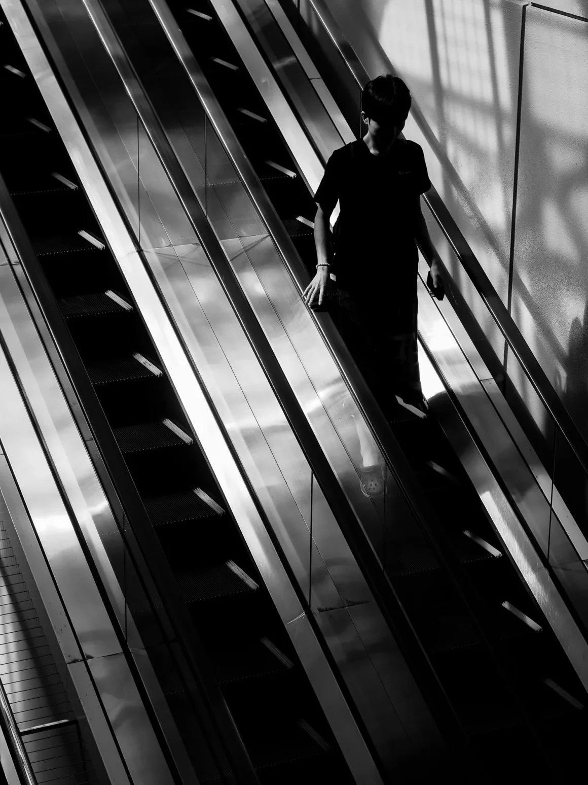 OM System PEN İncelemesi: Tanıdık Ama Son Derece Şık 50 A person in a black t-shirt descends a metal escalator, captured in a high-contrast black and white shot.