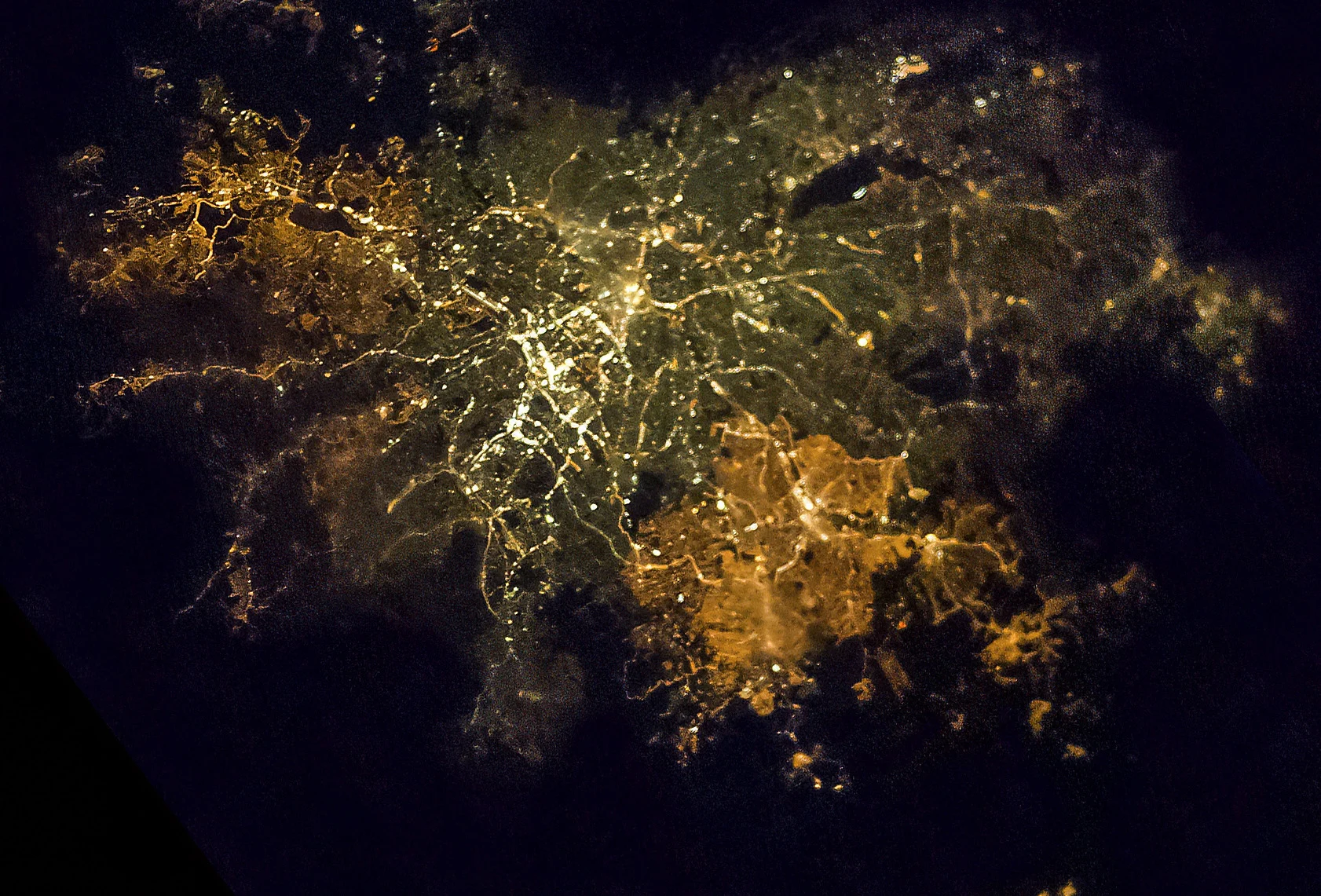 Astronotun Önce-Sonra Fotoğrafları Kentlerin Turuncudan Beyaz Işığa Geçişini Gösteriyor 23 A nighttime aerial view of a sprawling city, showing a dense network of bright yellow and white street lights against a dark background.