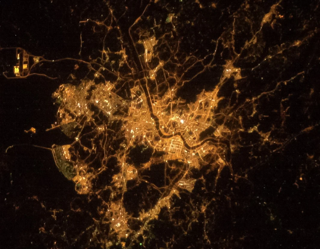 Astronotun Önce-Sonra Fotoğrafları Kentlerin Turuncudan Beyaz Işığa Geçişini Gösteriyor 25 An aerial night view of a brightly lit city, showing a network of illuminated roads and buildings against a dark background.