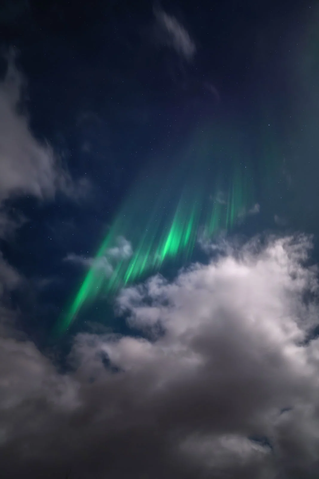 Astronomy Photographer of the Year 2026: Bu Dünyadan Olmayan 31 Kazanan 26 Bright green aurora borealis streaks across a dark night sky filled with scattered clouds and visible stars.
