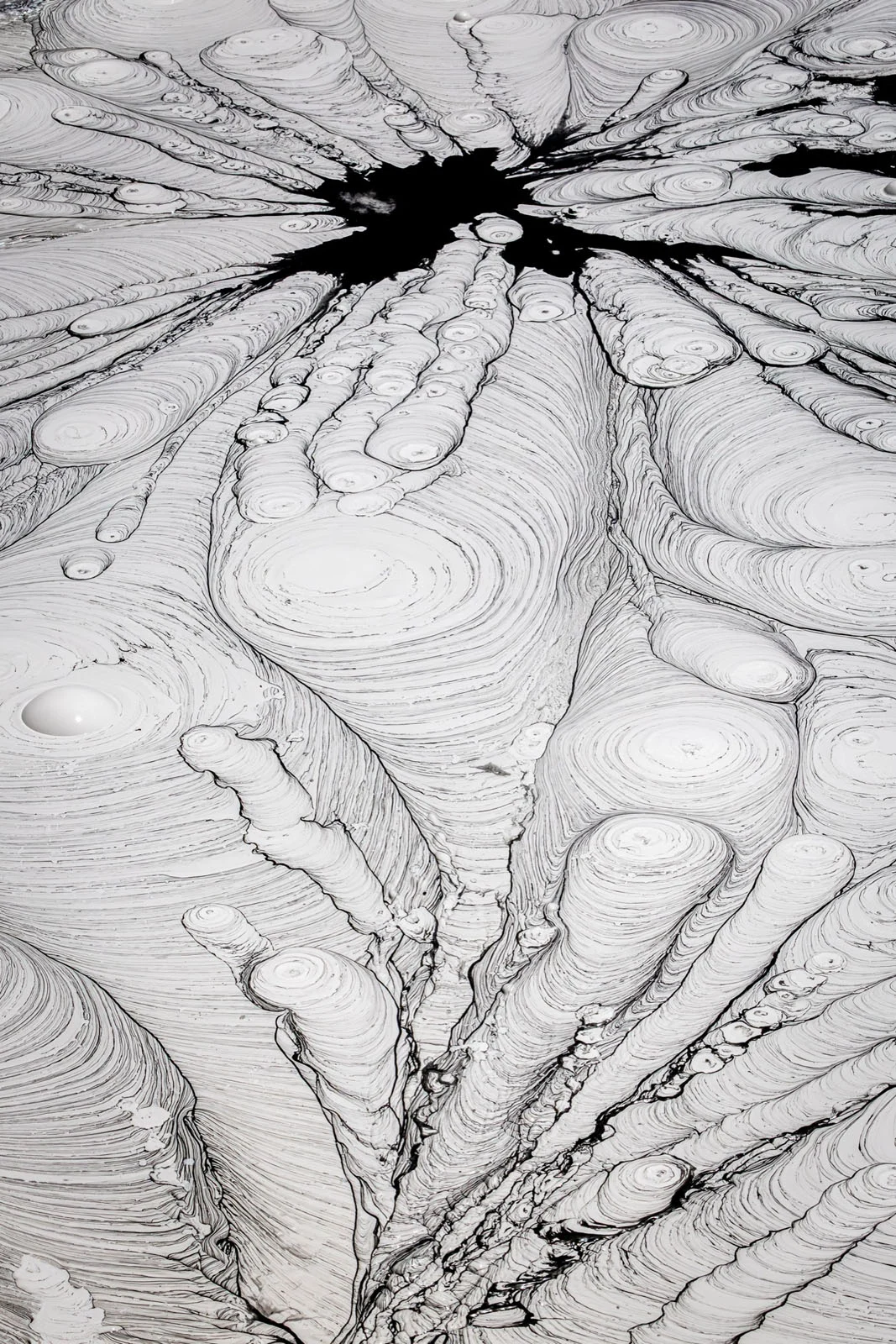 Natural Landscape Photography Awards 2026’nın Kazananları Açıklandı 79 A high-angle view of a thick, light-gray liquid surface featuring concentric circular patterns and a dark, irregular opening at the top.