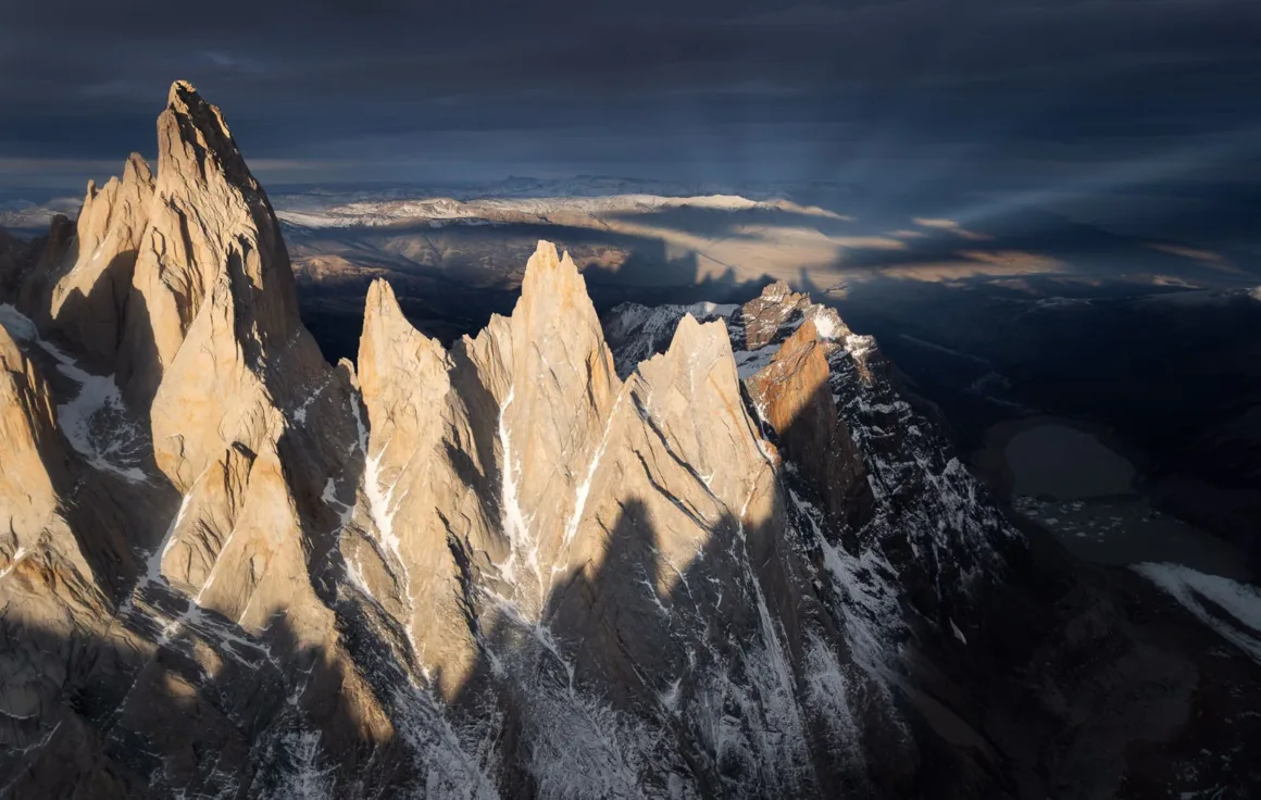 Natural Landscape Photography Awards 2026’nın Kazananları Açıklandı 43 Altın renkli güneş ışığı, karla kaplı sivri granit dağ zirvelerini koyu ve dramatik bir gökyüzü önünde aydınlatıyor.