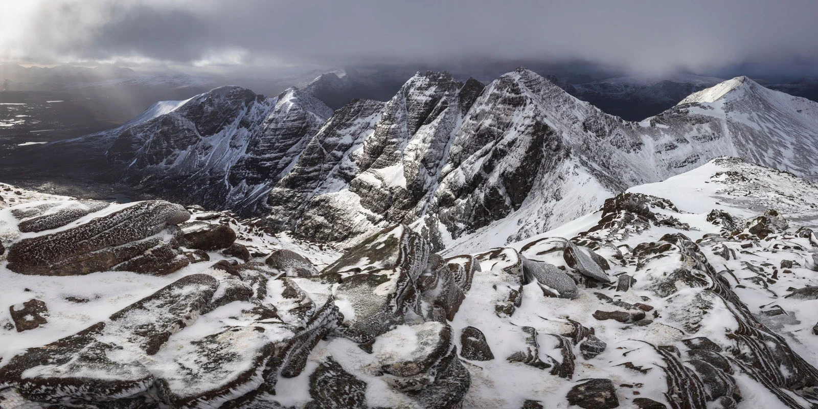 Natural Landscape Photography Awards 2026’nın Kazananları Açıklandı 72 A high-angle view of rugged, snow-dusted mountain peaks under a cloudy, dramatic sky with light breaking through.