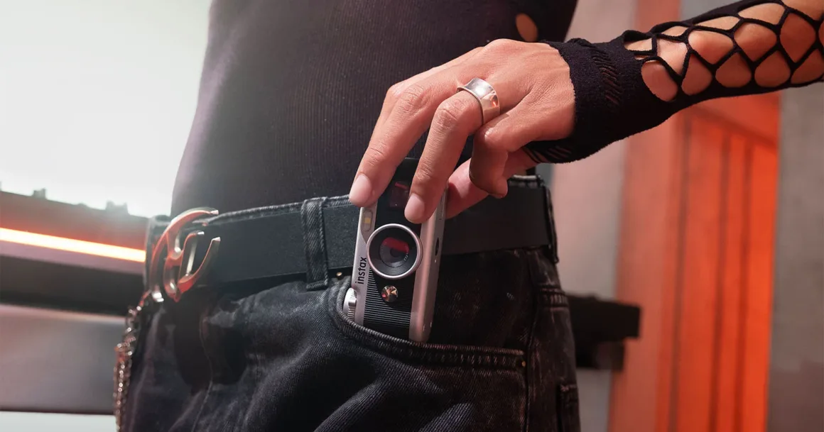 Fujifilm Instax Pal 2, Tuhaf Selefinden Tamamen Farklı Görünüyor 21 Siyah üst ve kot pantolon giyen bir kişi küçük gümüş kamerayı cebinin önünde tutuyor.