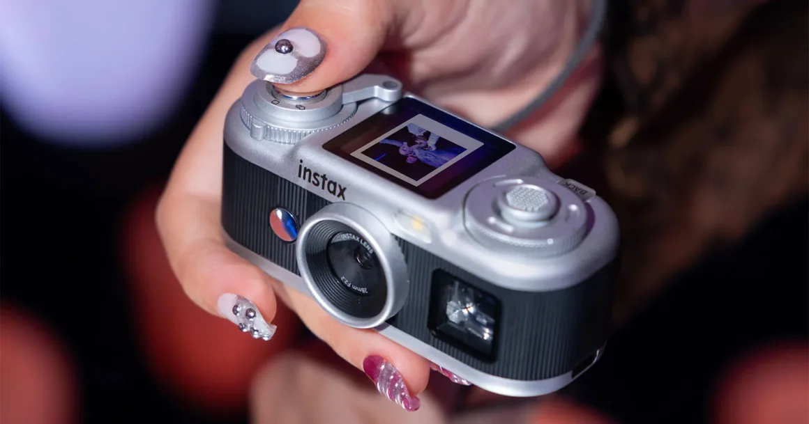 Fujifilm Instax Pal 2, Tuhaf Selefinden Tamamen Farklı Görünüyor 20 Bir kişi gümüş-siyah Instax kamerayı tutarken arka ekrandaki küçük fotoğrafı gösteriyor.