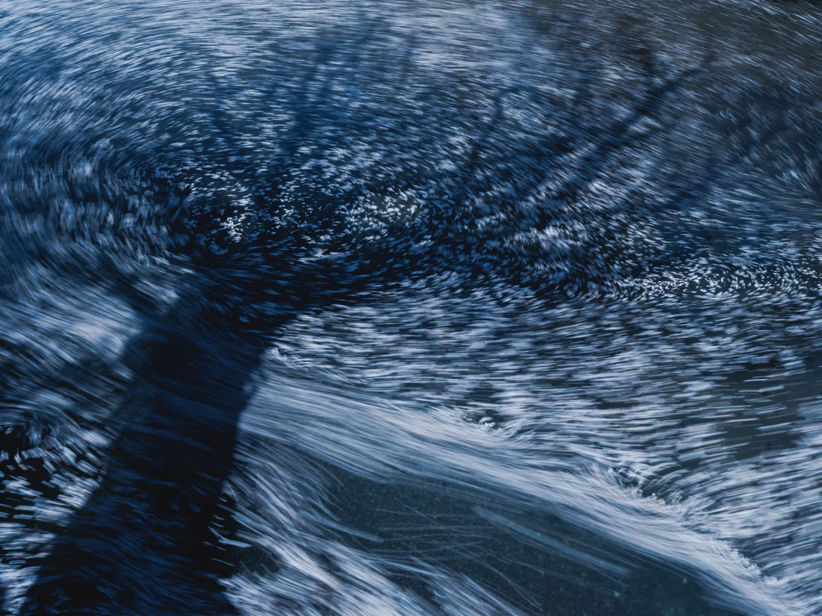 Natural Landscape Photography Awards 2026’nın Kazananları Açıklandı 73 A long-exposure shot of water flowing over a dark, submerged surface, creating swirling, blurred white streaks.