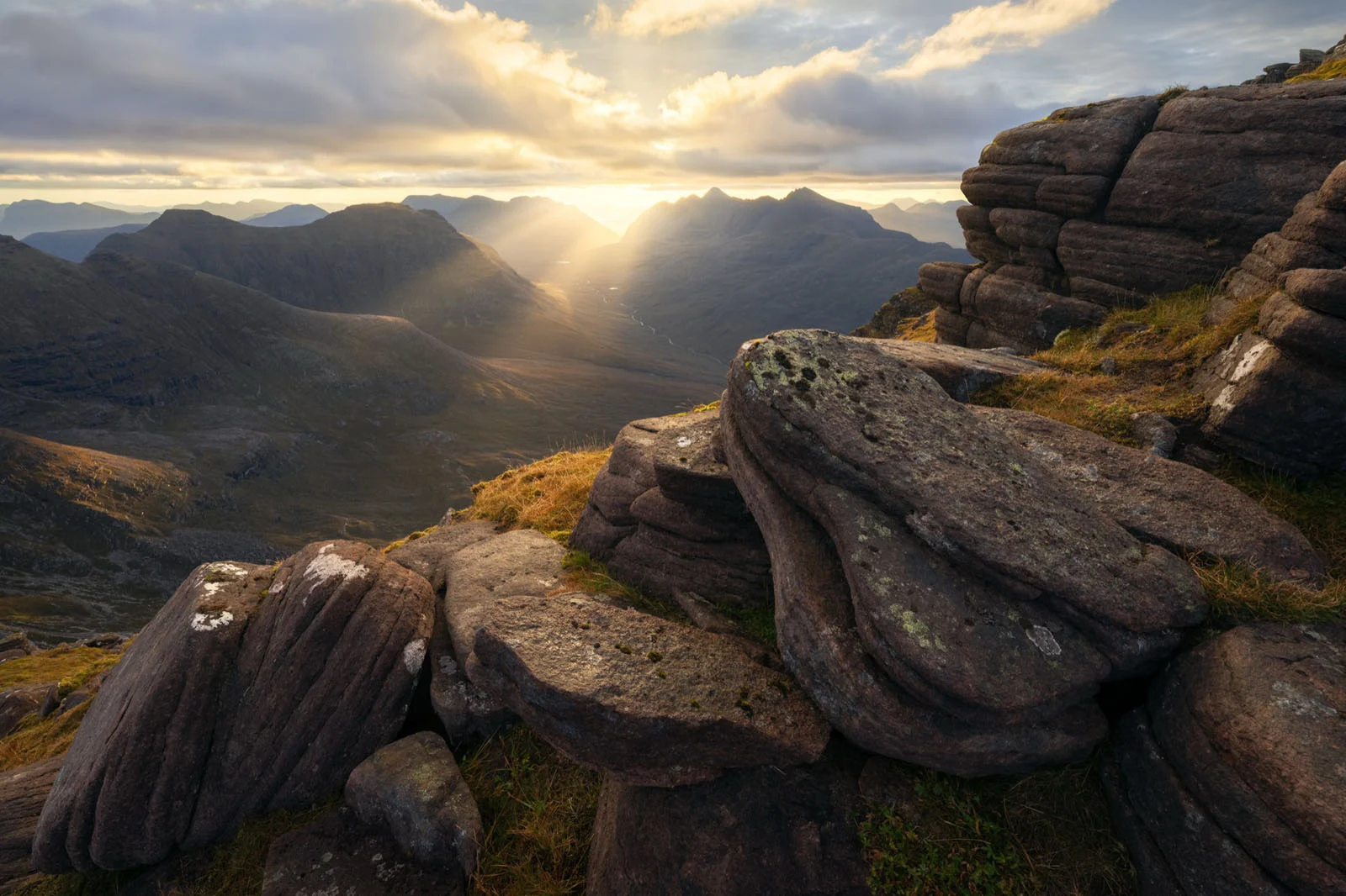 Natural Landscape Photography Awards 2026’nın Kazananları Açıklandı 91 Sunlight streams through clouds over a deep mountain valley, framed by large, layered rock formations in the foreground.