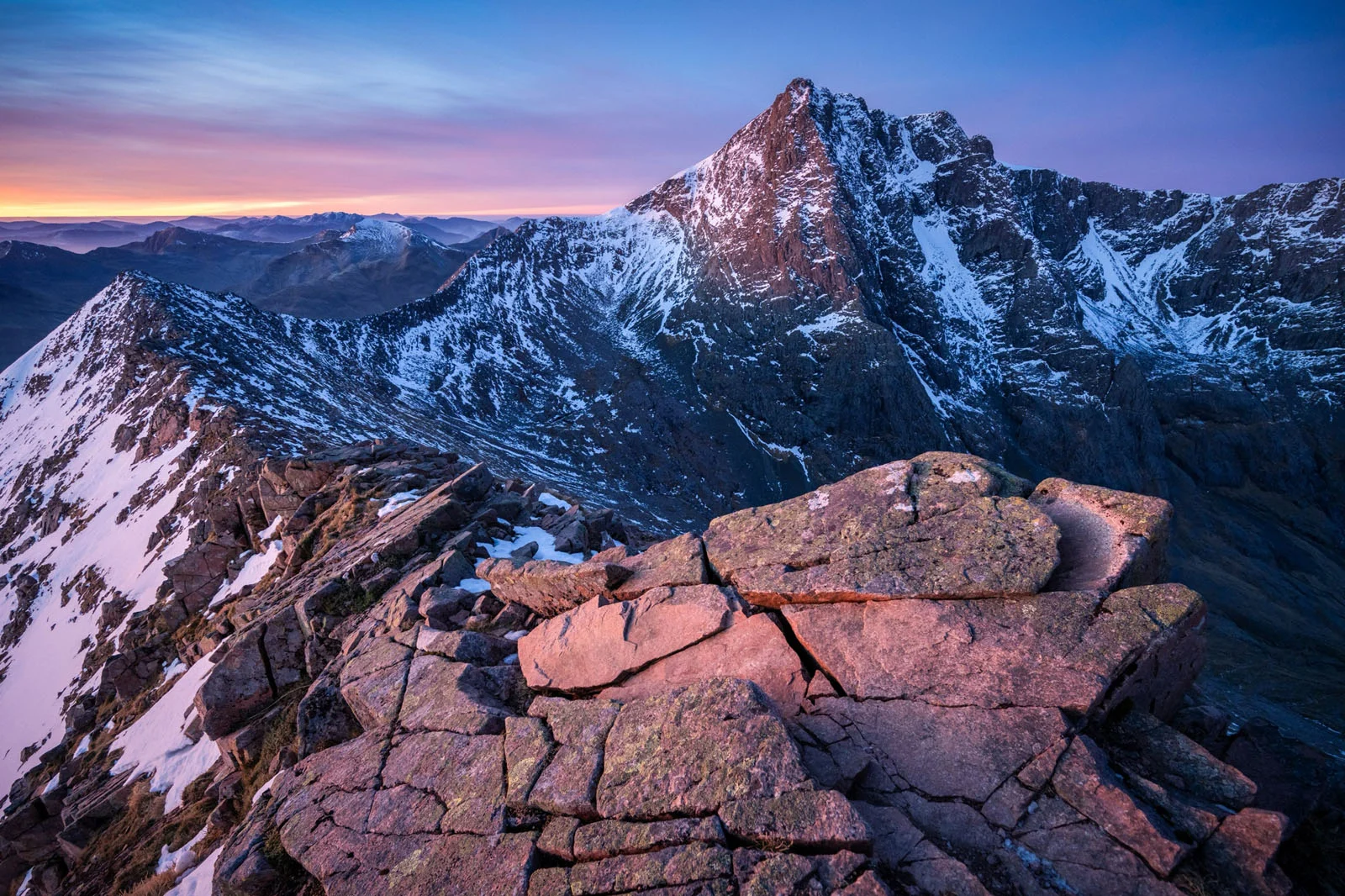 Natural Landscape Photography Awards 2026’nın Kazananları Açıklandı 93 A rocky, snow-dusted mountain ridge leads toward a towering, jagged peak under a colorful sunrise sky.