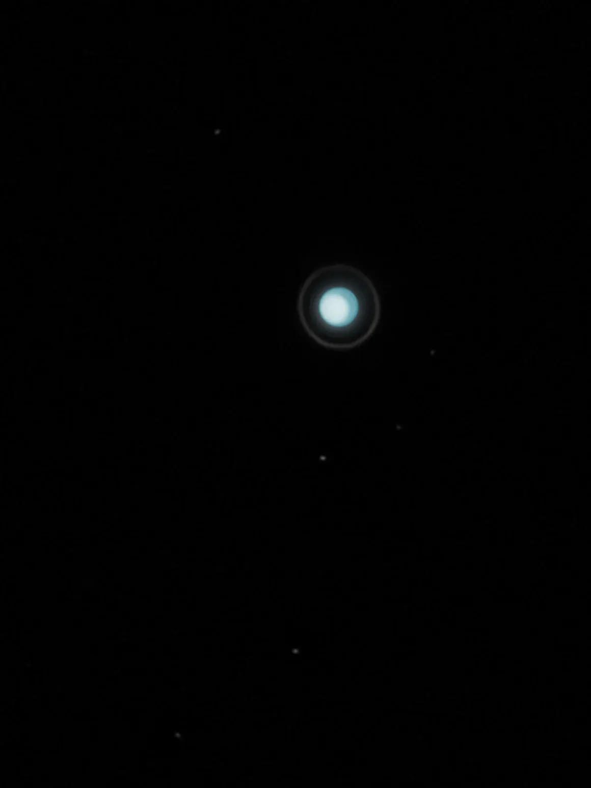 Astronomy Photographer of the Year 2026: Bu Dünyadan Olmayan 31 Kazanan 37 A bright, pale blue planet with a faint ring system is centered against a dark black background, surrounded by several small stars.