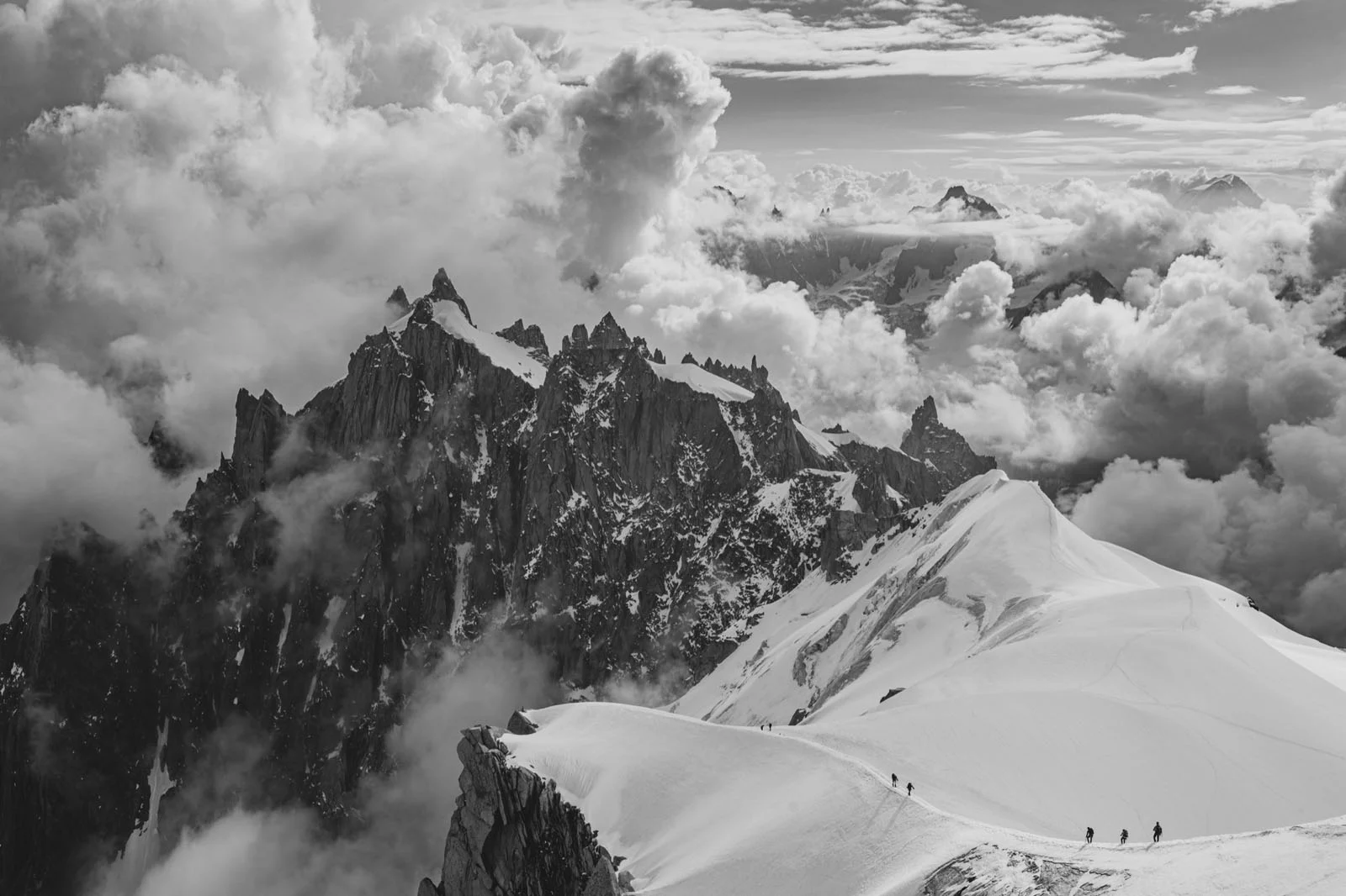 Natural Landscape Photography Awards 2026’nın Kazananları Açıklandı 82 A group of mountaineers traverses a snow-covered ridge beneath dramatic, cloud-filled skies and jagged mountain peaks.