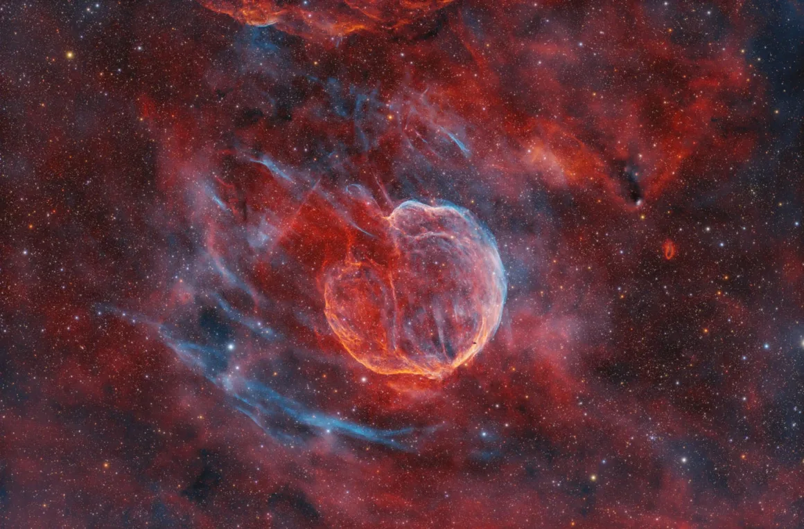 Astronomy Photographer of the Year 2026: Bu Dünyadan Olmayan 31 Kazanan 23 A glowing, heart-shaped nebula with intricate red and blue filaments sits amidst a dense field of stars and diffuse gas.