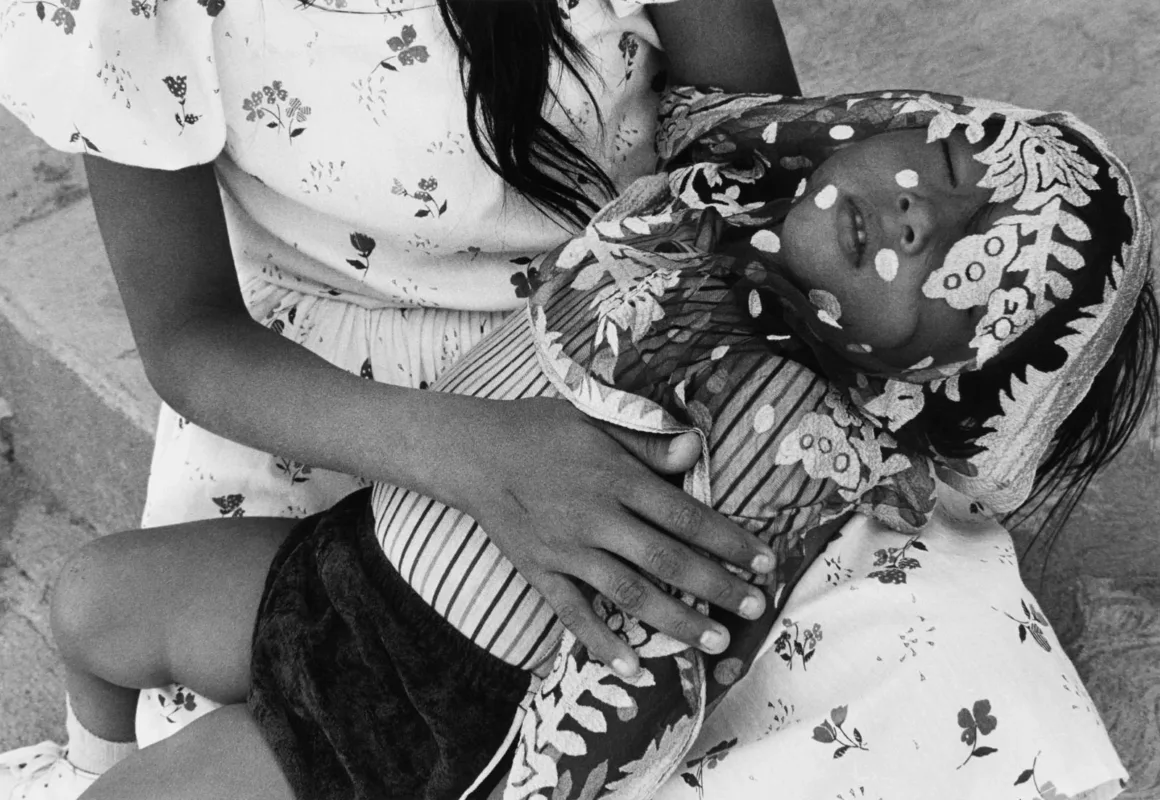 Graciela Iturbide, Leica Hall of Fame’in 15. Üyesi Oldu 19 Çiçek desenli elbise giyen bir kişi, yüzünün bir bölümü desenli başörtüsüyle kaplı uyuyan bir çocuğu kucağında tutuyor.