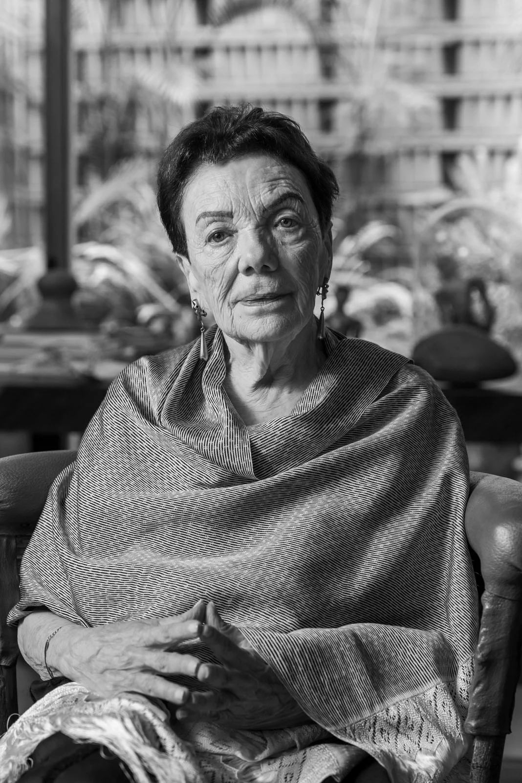 Graciela Iturbide, Leica Hall of Fame’in 15. Üyesi Oldu 24 Kısa koyu saçlı yaşlı bir kadın, çizgili şal ve sallantılı küpelerle ellerini birleştirmiş şekilde oturuyor.