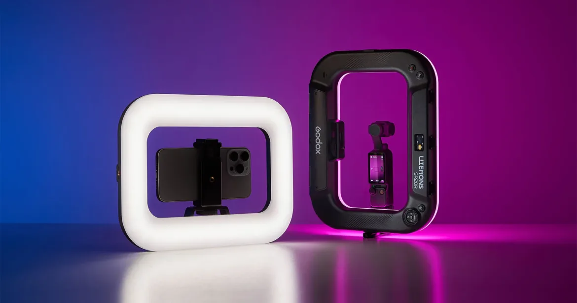 Two rectangular ring lights stand on a surface against a blue and purple gradient background, with a smartphone mounted in the left light and a small gimbal camera in the right light.