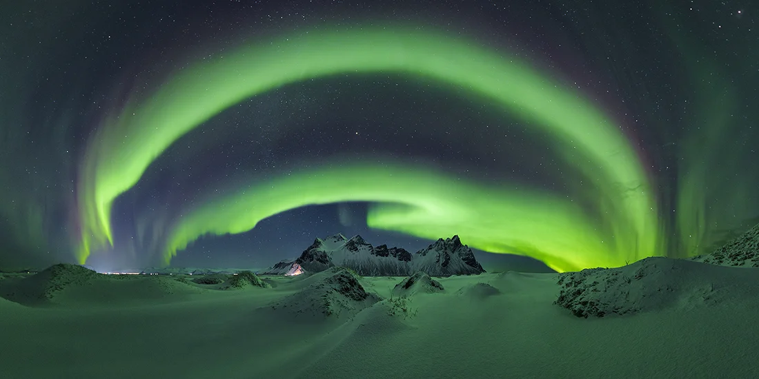 Epson International Pano Awards 2026 Kazananları Açıklandı 22 Canlı yeşil aurora, karla kaplı kumullar ve sivri koyu dağların üzerindeki yıldızlı gece gökyüzünde geniş bir yay oluşturuyor.