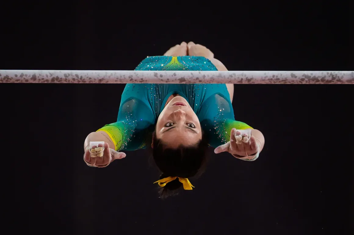 Glasgow 2026’da Bir Spor Fotoğrafçısının Çantasında Neler Vardı? 23 Turkuaz ve sarı mayo giyen kadın jimnastikçi asimetrik paralelde alttan görülen açıyla hareket yapıyor.