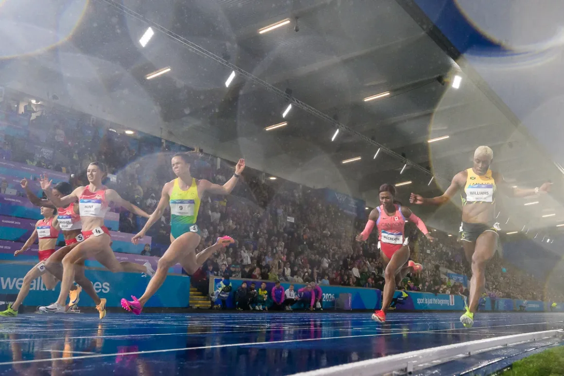 Glasgow 2026’da Bir Spor Fotoğrafçısının Çantasında Neler Vardı? 27 Beş kadın atlet, seyircilerle dolu stadyumda ıslak pist üzerinde bitiş çizgisine doğru sprint atıyor.