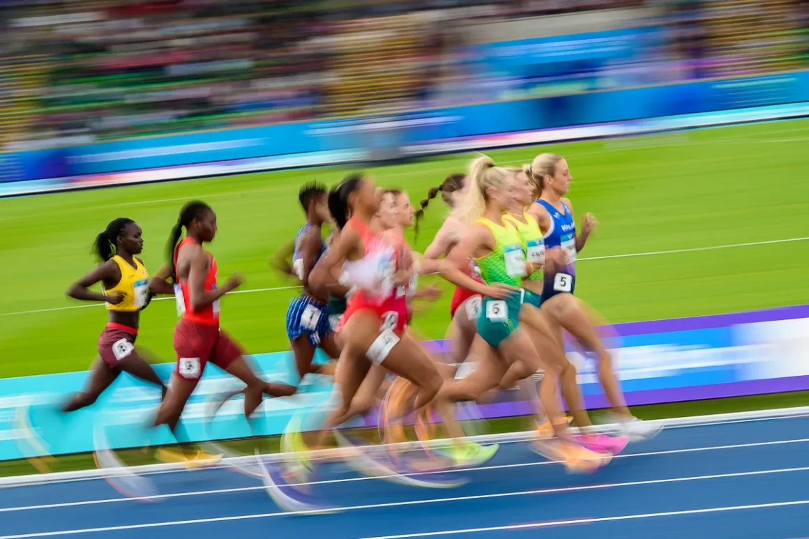 Glasgow 2026’da Bir Spor Fotoğrafçısının Çantasında Neler Vardı? 20 Farklı renklerde formalar giyen kadın atletler mavi pist üzerinde yarışıyor.