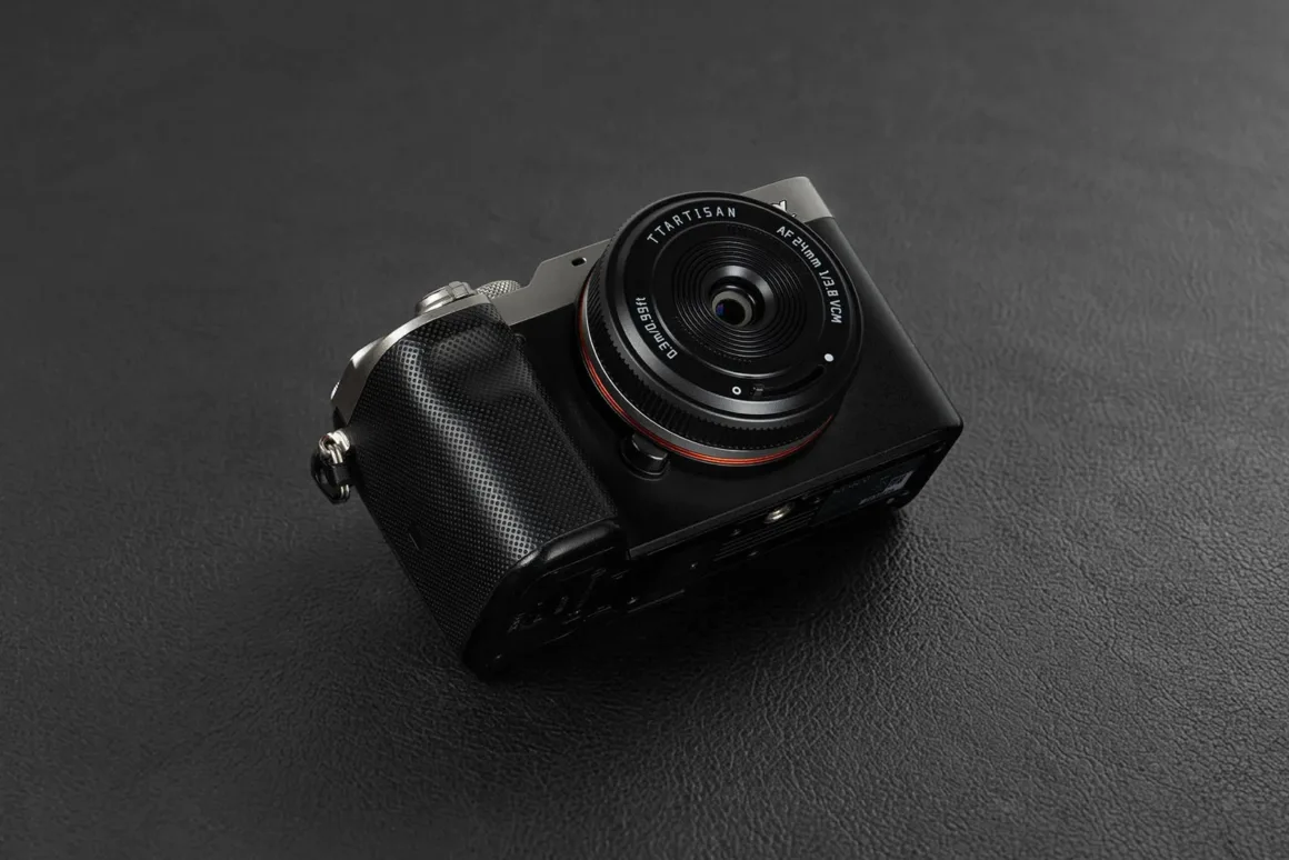 TTArtisan AF 24mm f/3.8 Mini: Sony E Mount için 57 Gramlık Pancake Objektif 23 TTArtisan AF 24mm f/3.8 VCM objektif takılı siyah aynasız fotoğraf makinesi, koyu ve dokulu bir yüzey üzerinde duruyor.