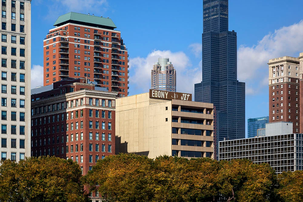 Chicago şehir silüetinde birçok yüksek bina arasında, tepesinde EBONY ve JET yazıları bulunan açık renkli yapı öne çıkıyor.