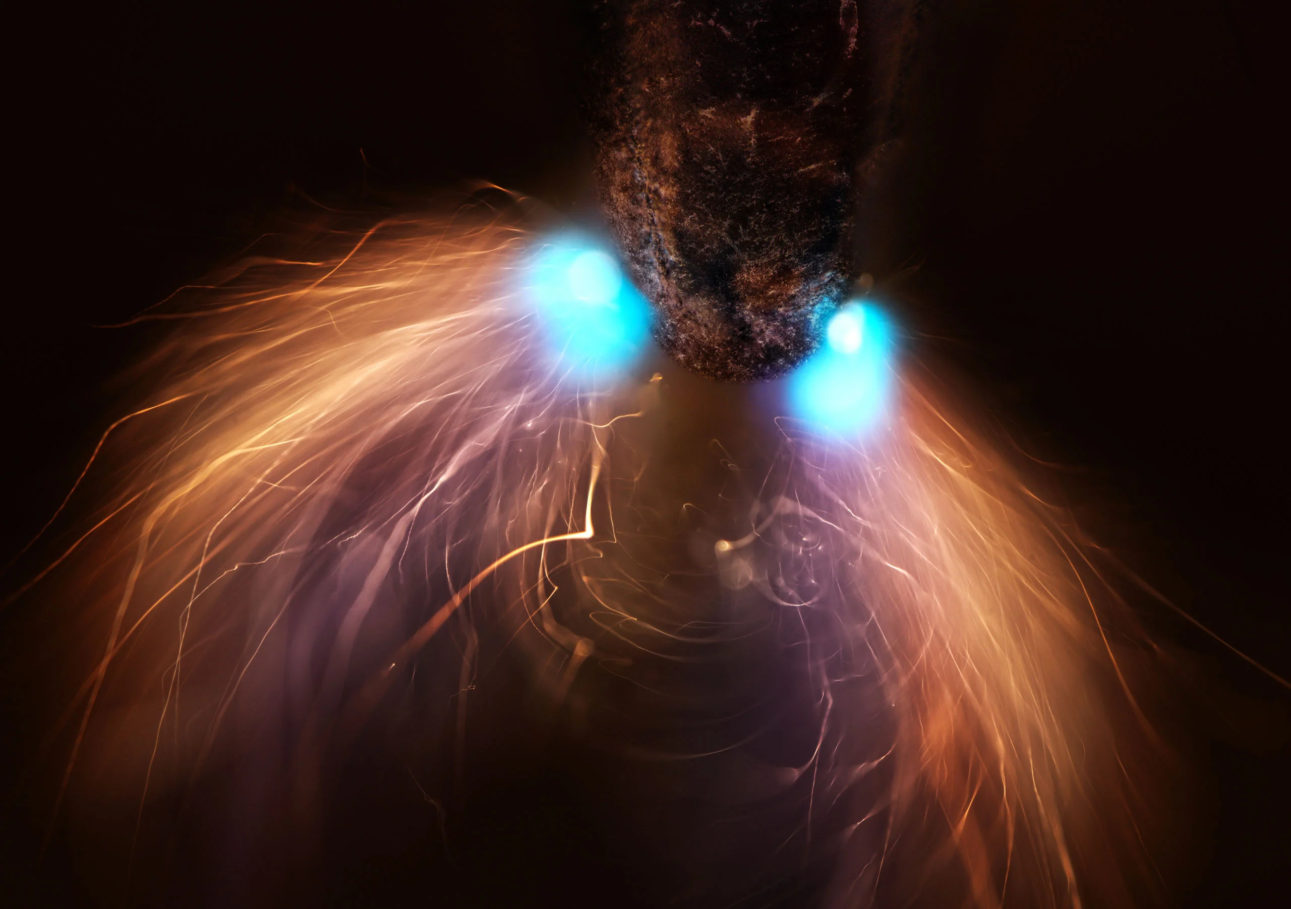 Nikon Small World 2026 Kazananları Açıklandı: Mikroskobik Dünyadan Büyüleyici Görüntüler 26 A dark, textured object emits two bright blue light sources, surrounded by long, flowing streaks of orange sparks.