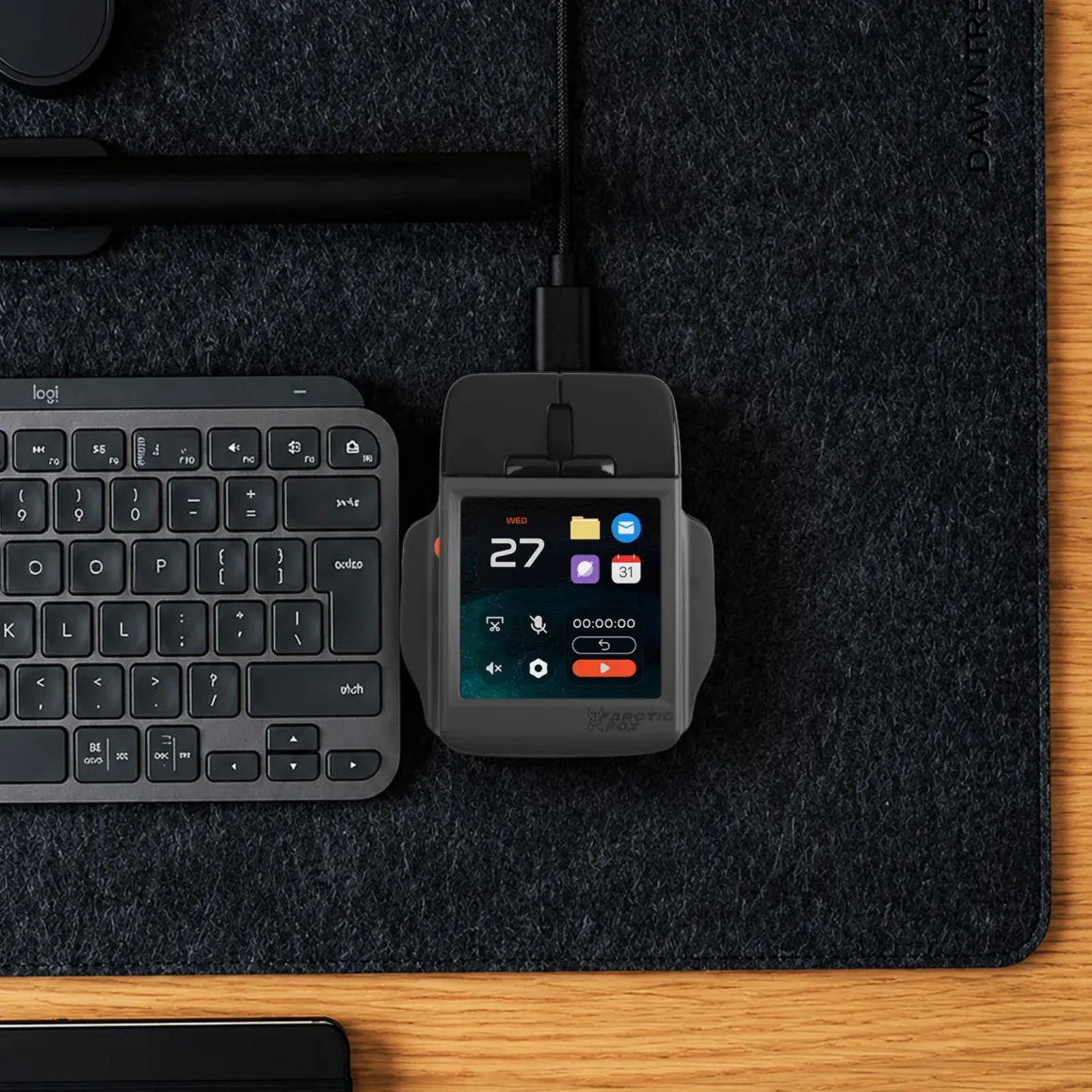 Super Mouse Tanıtıldı: Dokunmatik Ekranlı Fare Üretkenlik Merkezi Olmayı Hedefliyor 29 A top-down view shows a computer mouse with an integrated touchscreen display, positioned next to a Logitech keyboard on a dark felt desk mat.
