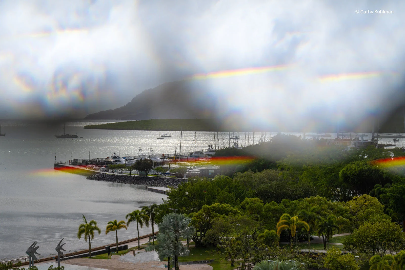 Lensbaby Omni Color II ve Omni Crystal II ile Çekim Sırasında Yaratıcı Efektler 26 A harbor with boats and a marina is viewed through a window with prominent rainbow-colored lens flare and light refraction.