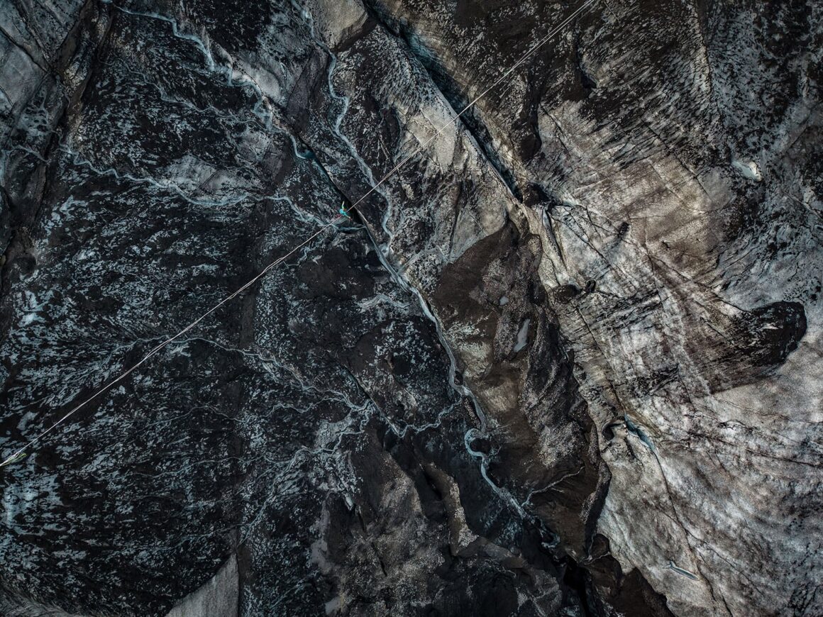 AOP Emerging Talent Awards 2026: Altın Ödül Austin Bradley’nin 21 Havadan çekilmiş görüntüde bir kişi, derin ve karanlık bir buzul yarığının üzerinde gerilmiş highline üzerinde yürüyor.