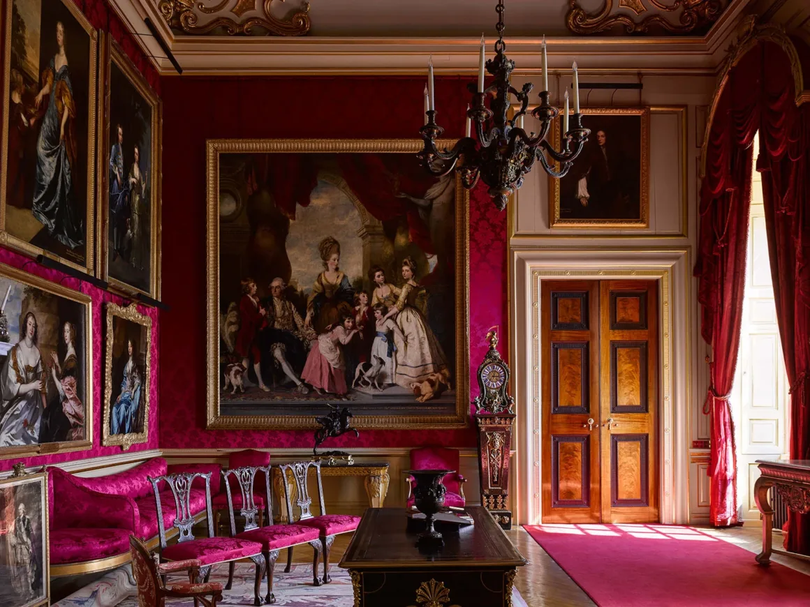 Architecture Photography MasterPrize 2026 Kazananları Açıklandı 40 Kırmızı damask duvarlı görkemli salonda büyük bir aile portresi, süslü mobilyalar, avize ve çift ahşap kapılar yer alıyor.