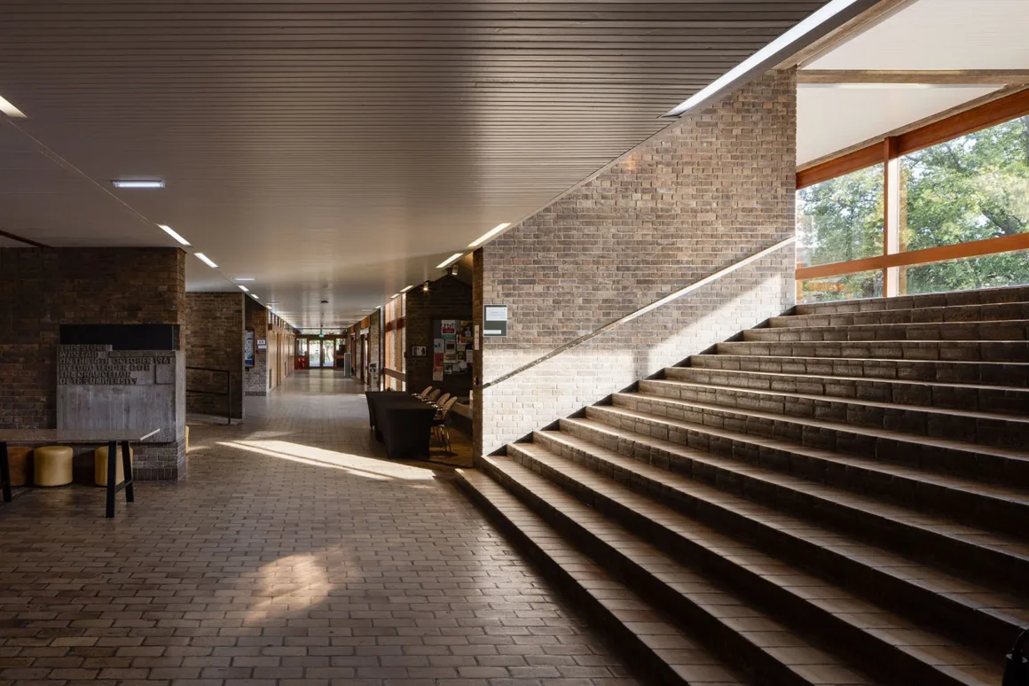 Architecture Photography MasterPrize 2026 Kazananları Açıklandı 36 Tuğla duvarlı ve zeminli geniş iç koridorda sağ tarafta büyük merdivenler, uzun alçak tavanda ise gömme aydınlatmalar yer alıyor.
