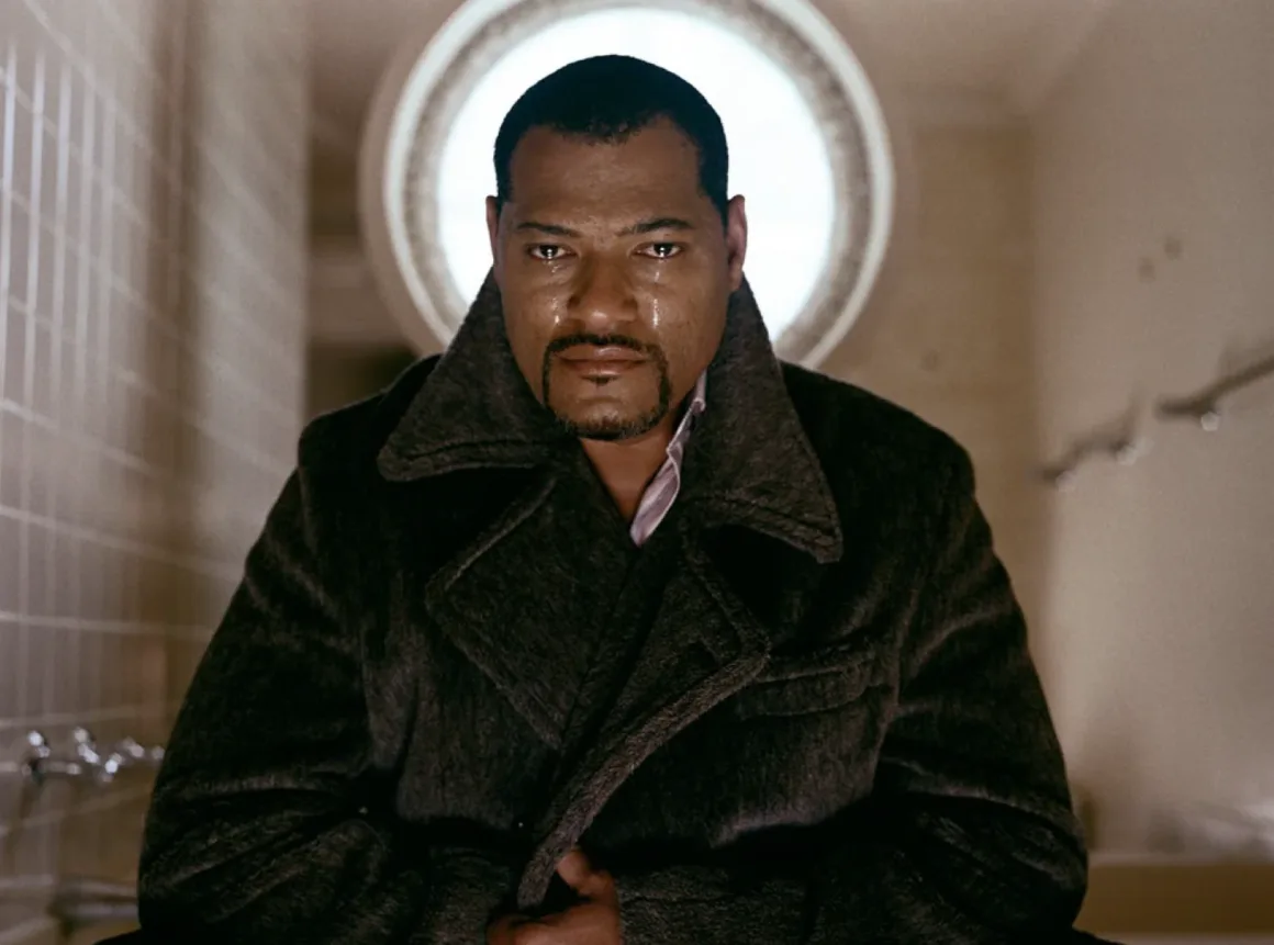 Sam Taylor-Johnson’ın “She Was I” Sergisi: Kimlik, Benlik ve Portre 15 Sam Taylor-Johnson Crying Men serisinde Laurence Fishburne portresi, 2002
Laurence Fishburne, gözleri yaşlarla dolu halde, koyu renkli yün paltosuyla dairesel bir pencerenin önünde duruyor.