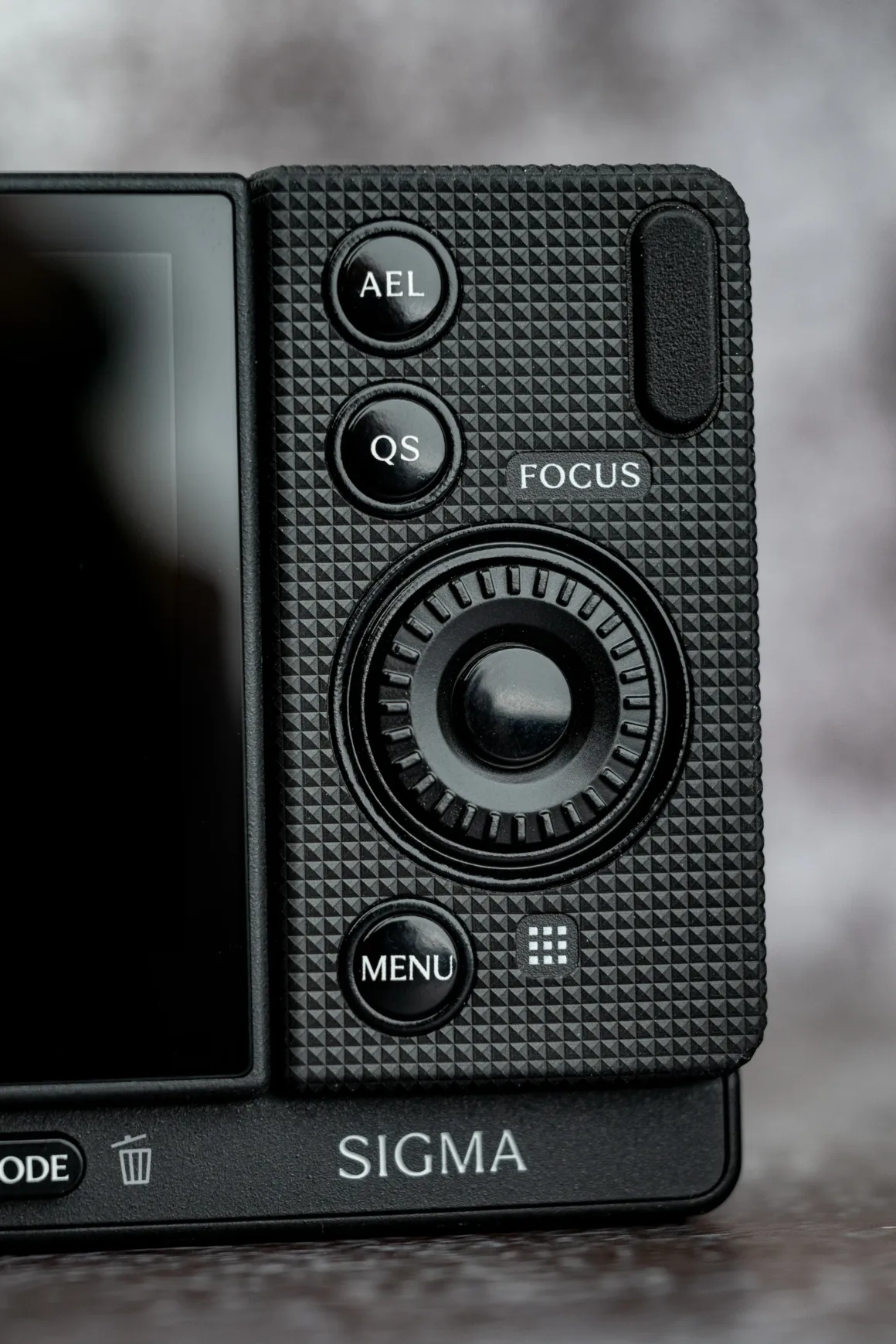Sigma FP2 İncelemesi: Tuhaf Tasarım, Güçlü Hibrit Performans 25 Siyah Sigma kameranın arkasında AEL, QS, FOCUS ve MENU düğmeleri ile ortada kontrol kadranı görülüyor.