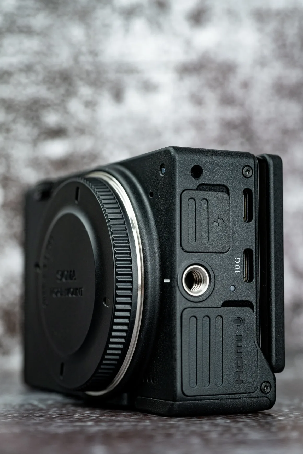 Sigma FP2 İncelemesi: Tuhaf Tasarım, Güçlü Hibrit Performans 22 Siyah bir dijital kamera gövdesinin yan görünümünde tripod bağlantısı ve 10G ile HDMI etiketli çeşitli bağlantı noktaları görülüyor.