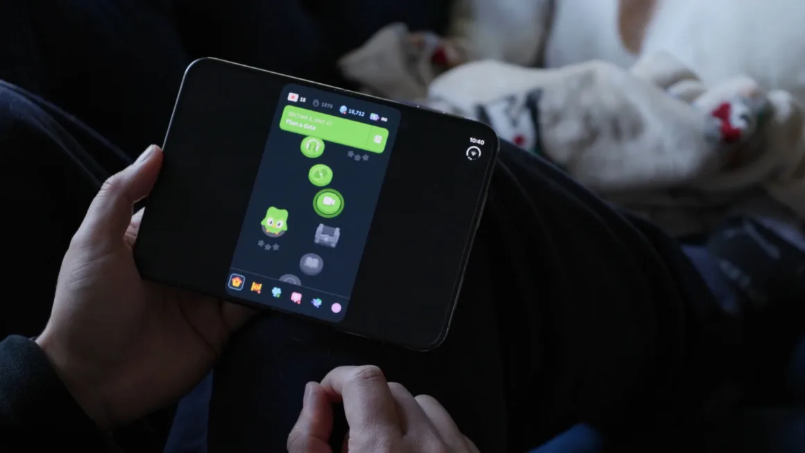 iPhone Duo İncelemesi: Etkileyici Tasarım, Kaçınılmaz Tavizler 22 Bir kişi, Duolingo uygulamasında devam eden dil öğrenme yolunu gösteren katlanabilir akıllı telefonu tutuyor.