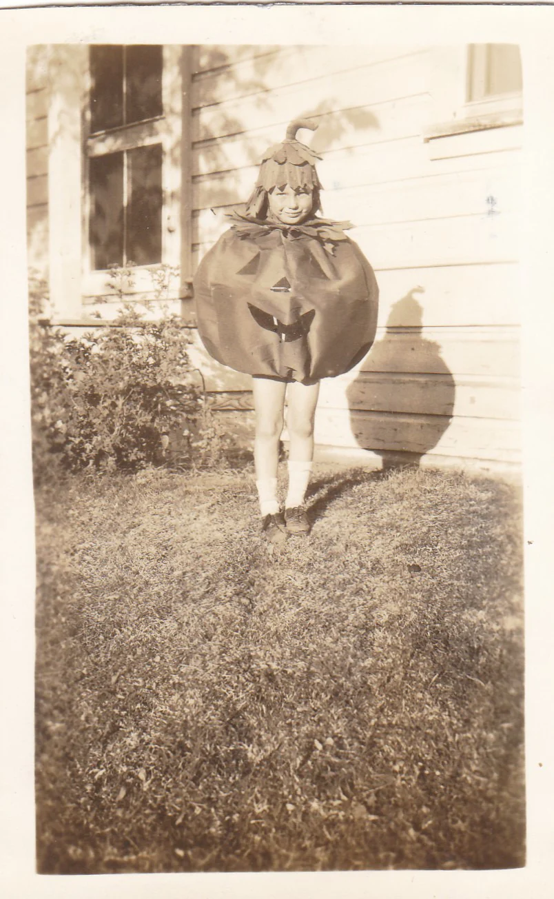 20. Yüzyıl Ortalarından Tekinsiz Halloween Fotoğrafları 24 Yuvarlak balkabağı kostümü ve şapkası giyen çocuk bir evin önündeki çimlerde duruyor