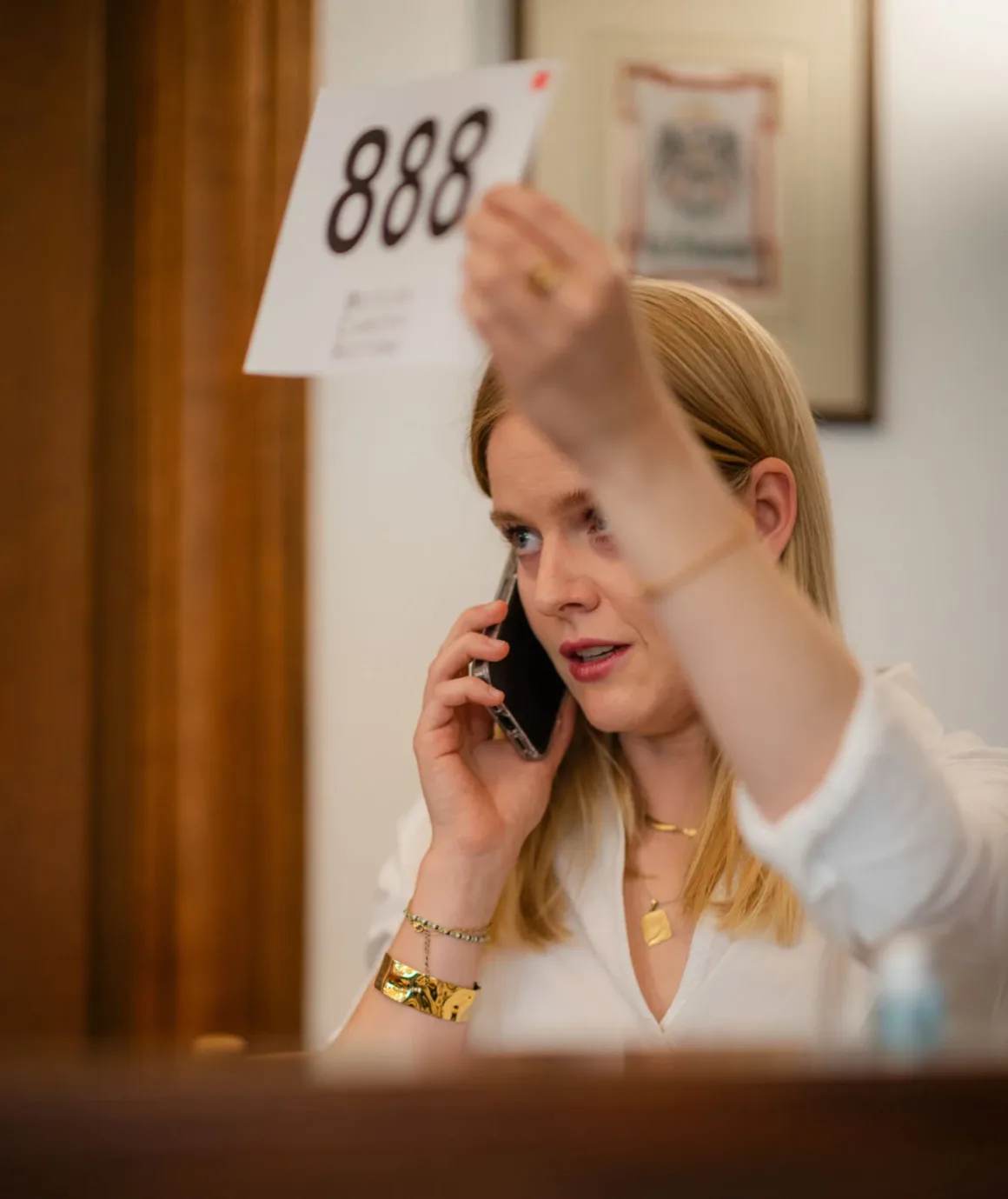 1923 Üretimi Leica 0-Series, 4,25 Milyon Euroya Satıldı 23 A woman with blonde hair holds up a white sign with the number 888 while talking on a smartphone.