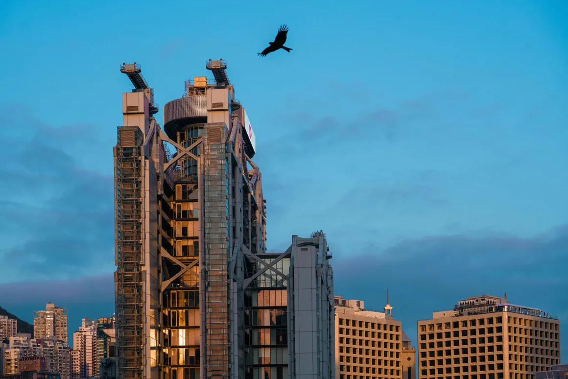 Architecture Photography MasterPrize 2026 Kazananları Açıklandı 35 Bir kuş Hong Kong’daki HSBC Main Building’in üzerinde uçarken diğer gökdelenler mavi ve bulutlu gökyüzüne karşı görülüyor.