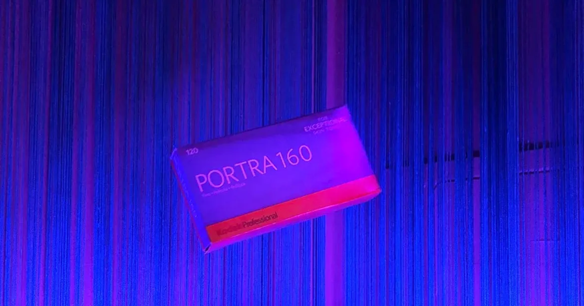 A box of Kodak Professional Portra 160 120 film floats against a background of vertical blue and purple string curtains.