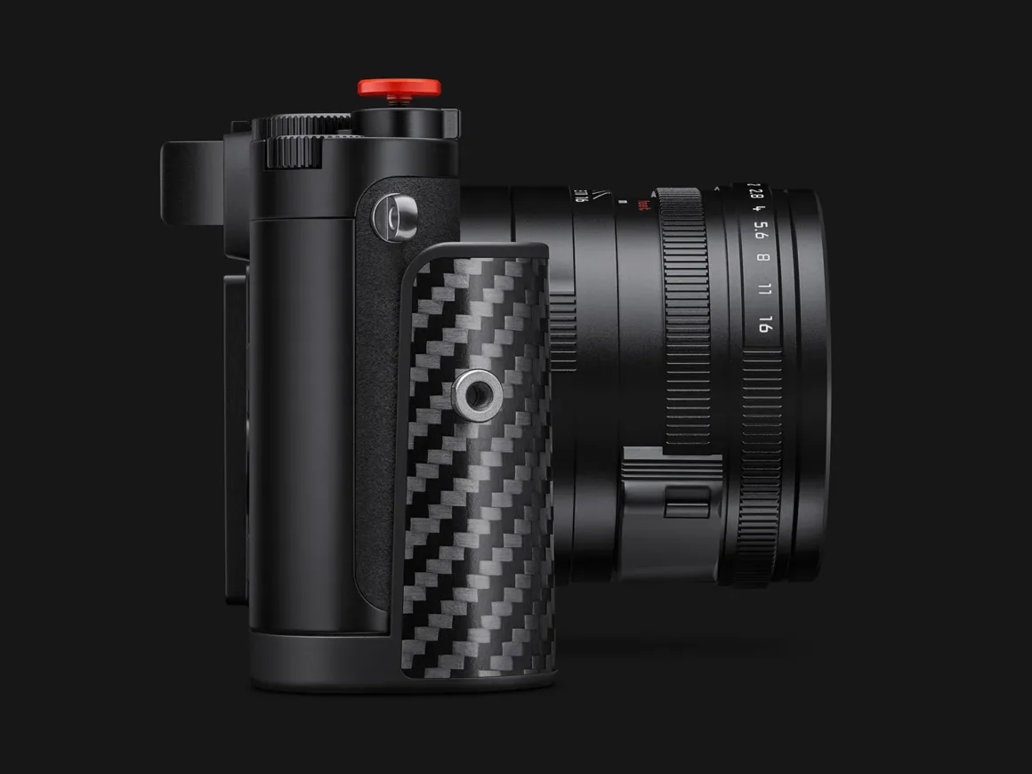 Leica Q3 43 Formula 1 Edition: Karbon Fiber Detaylı Özel Seri 27 Karbon fiber tutma bölümüne, kırmızı deklanşör düğmesine ve diyafram işaretleri görünen objektife sahip siyah fotoğraf makinesinin yandan görünümü.