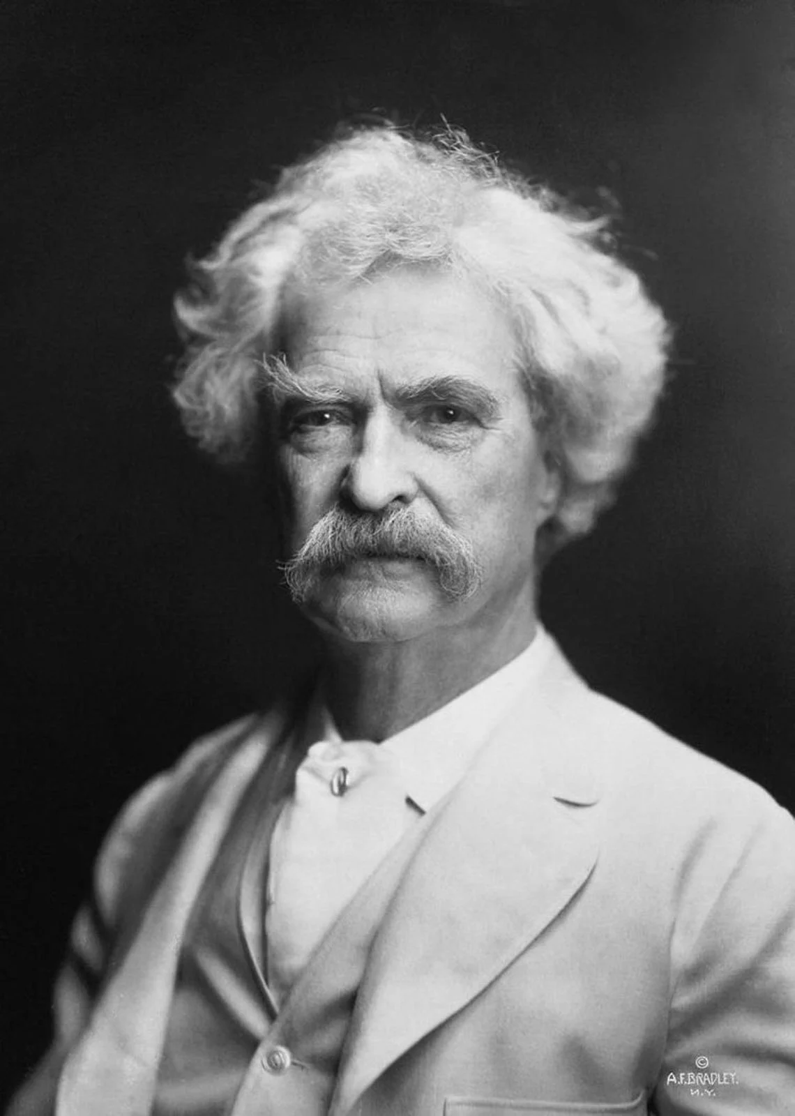 Fotoğraflarda Neden Gülümsüyoruz? Portre Geleneğinin Değişen Yüzü 25 Mark Twain'in kendine özgü dağınık beyaz saçları ve bıyığıyla, açık renk ceket giydiği siyah-beyaz portresi.