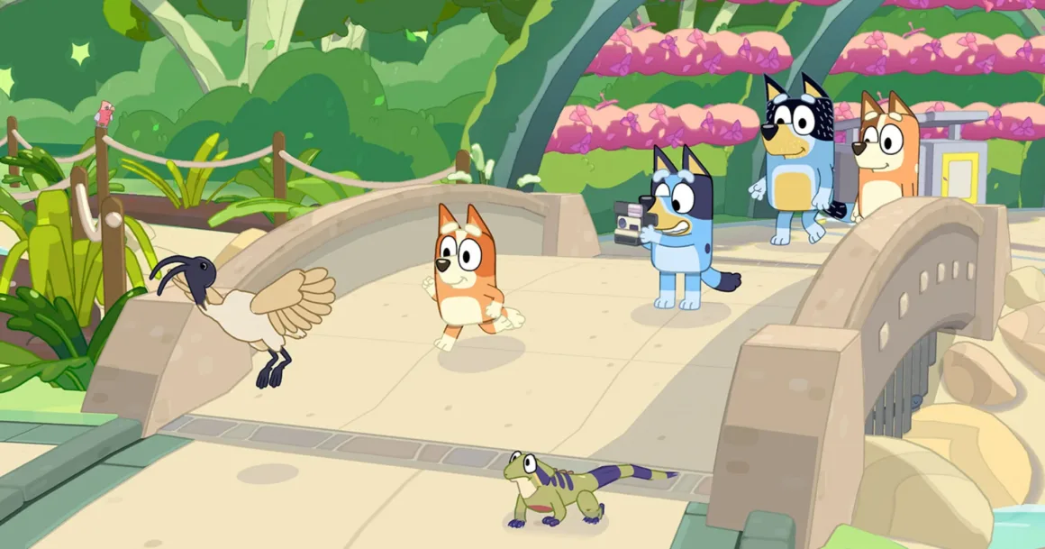 Bluey’s Happy Snaps, Çocuklara Fotoğrafçılığı Oyunla Sevdiriyor 19 Bluey, bir köprü üzerinde koşan Bingo'nun fotoğrafını çekerken yakında bir ibis ve kertenkele görülüyor; Bandit ve Chilli ise arkadan onları izliyor.